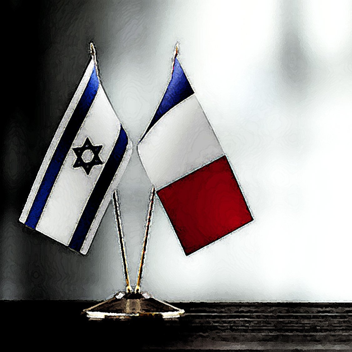 La imagen muestra dos banderas pequeñas en un soporte: una de Israel, que presenta la estrella de David en un fondo blanco y azul, y otra de Francia, con los colores azul, blanco y rojo dispuestos verticalmente. Las banderas están colocadas sobre una superficie oscura, y el fondo es difuso y claro, lo que resalta las banderas.