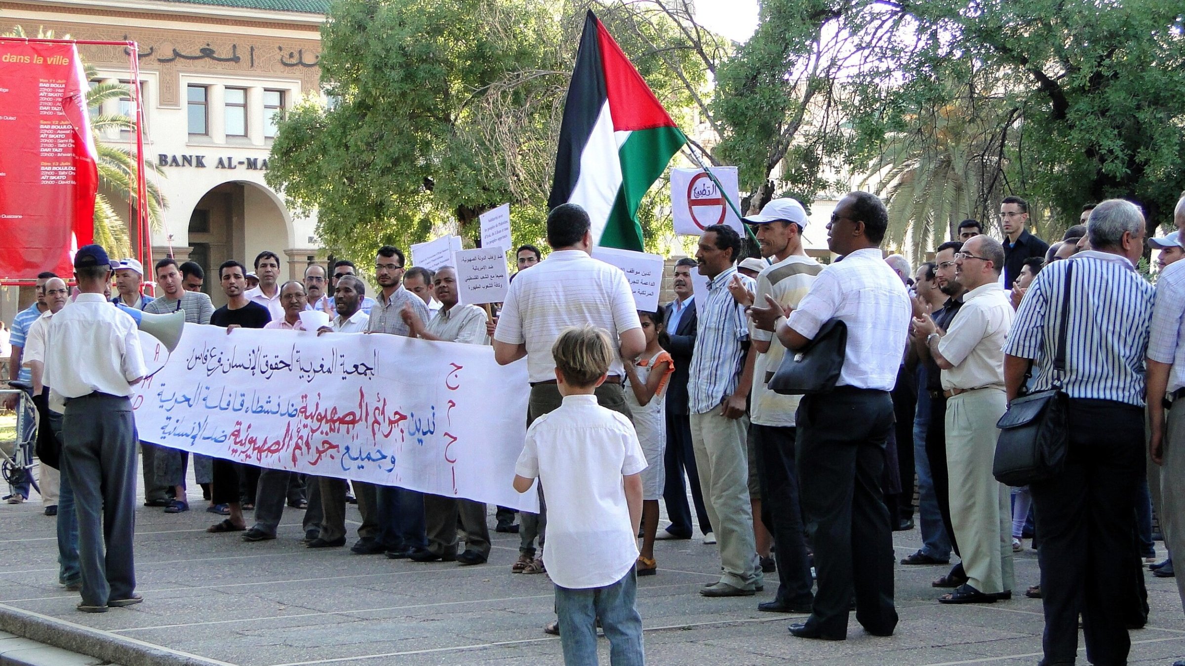Un gruppo di persone in protesta con bandiera palestinese e striscioni.