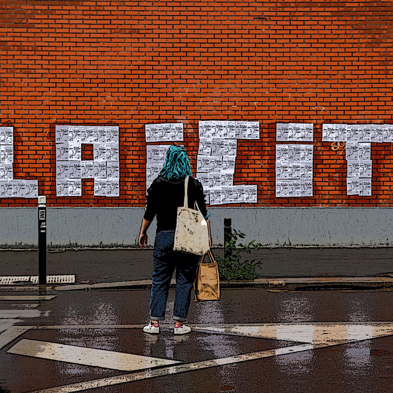 The image shows a person standing in front of a brick wall on which the word "LAICITE" is prominently displayed in large, white, block letters. The individual appears to be wearing a turquoise headscarf and carries a bag, facing the wall. The ground is wet, suggesting it may have recently rained, and the scene includes elements indicating a city environment, such as street signs and a road marking in the foreground. The overall atmosphere combines urban art with a mood of contemplation or engagement with the word on the wall.