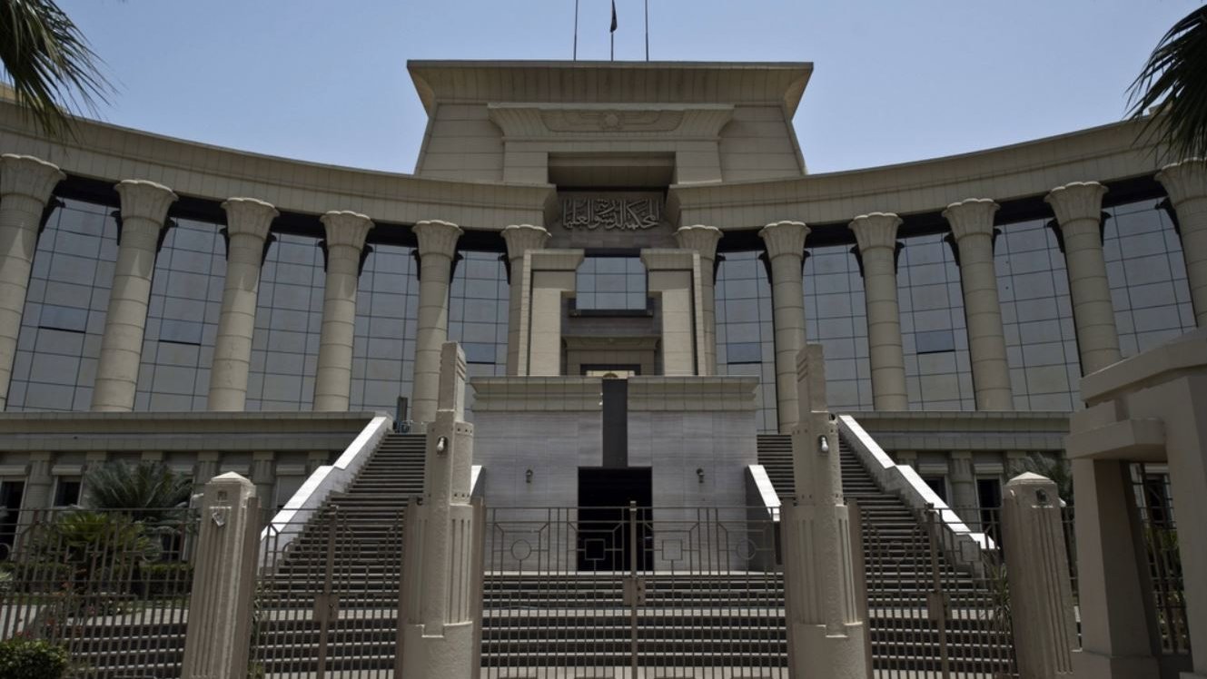 L'image montre un bâtiment imposant, probablement une institution judiciaire, avec une architecture moderne. La façade est ornée de colonnes majestueuses et de grandes fenêtres réfléchissantes, créant une impression de grandeur. Il y a des escaliers menant à l'entrée principale, qui semble être encadrée par des éléments décoratifs. Le ciel est dégagé, suggérant une journée ensoleillée. Des palmiers sont visibles sur les côtés, ajoutant une touche tropicale à l'environnement.