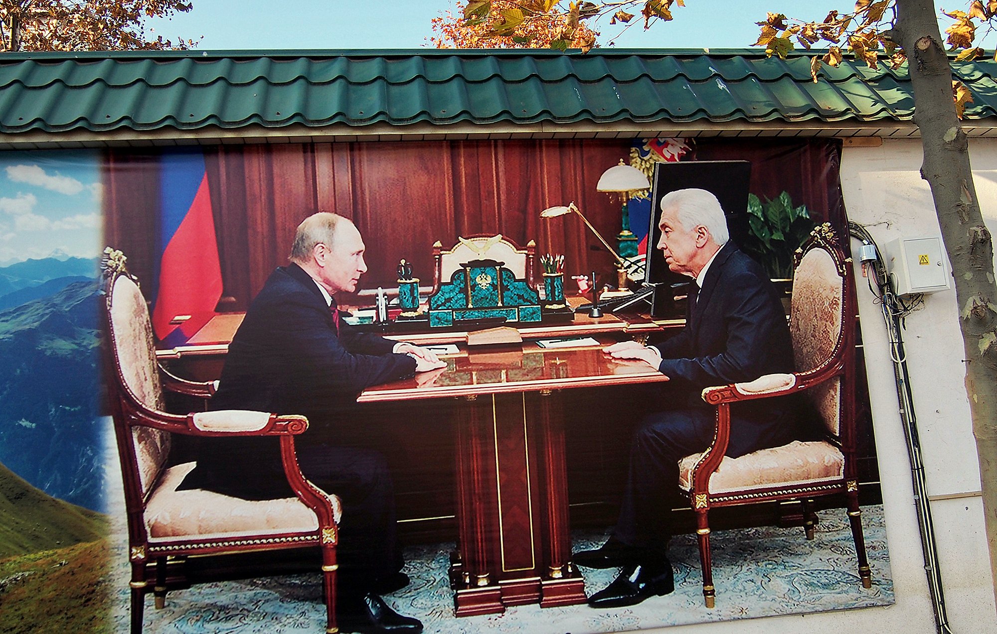 تظهر الصورة مشهدًا لمكتب يتواجد فيه شخصان يجلسان على جانبي طاولة كبيرة، يبدو أنهما يتحدثان أو يتناقشان. الخلفية تحتوي على أثاث مكتبي فاخر، مع تفاصيل مثل المصابيح والأدوات المكتبية. المنظر العام يعطي انطباعًا بالجدية والنقاش المهم بين الشخصين.