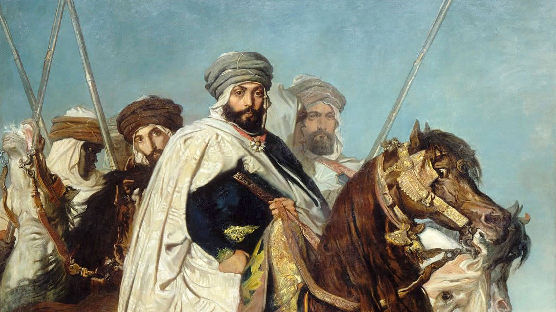 L'image représente un groupe de cavaliers, probablement d'origine orientale, habillés en costumes traditionnels. Au premier plan, un homme est monté sur un cheval majestueux, vêtu d'une tunique ornée et d'un turban. Il semble être le leader ou la figure centrale de ce groupe. Les autres cavaliers en arrière-plan portent également des tenues similaires et tiennent des lances, créant une impression de puissance et de bravoure. Le ciel en arrière-plan est clair, ajoutant une dimension dramatique à la scène. L'ensemble dégage une atmosphère historique et militaire.