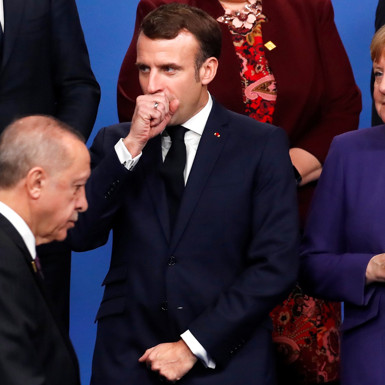 في الصورة، يظهر ثلاثة شخصيات بارزة في لقاء رسمي. في الجانب الأيسر، يوجد شخص يبدو أنه يتحدث أو يتفاعل مع الآخرين. في الوسط، يوجد شخص يرتدي بدلة ويظهر في وضعية تفكير أو تأمل، حيث قد يكون مشغولًا ببعض الأفكار. على اليمين، توجد شخصية أخرى ترتدي ملابس رسمية أيضًا، وتبدو متفائلة أو مهتمة بالحادثة. الخلفية تتكون من ألوان زاهية، مما يضفي طابعًا رسميًا على اللحظة.