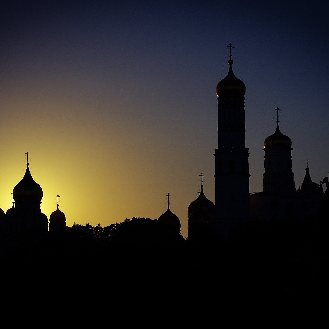 این تصویر نمایی از یک افق زیبا در هنگام غروب را نشان می‌دهد. در پس‌زمینه، خورشید به تدریج در حال غروب است و نور طلایی آن به صورت مجسمه‌ای در آمده که بر روی قله‌های ساختمان‌ها تابیده می‌شود. در جلو، ساختمان‌های مذهبی با گنبدها و برج‌های بلند، به صورت سیاه‌چرمی در برابر نور زمینه قرار دارند. سایه‌های این بناها، محیط را به فضایی رازآلود و باشکوه تبدیل کرده‌اند.