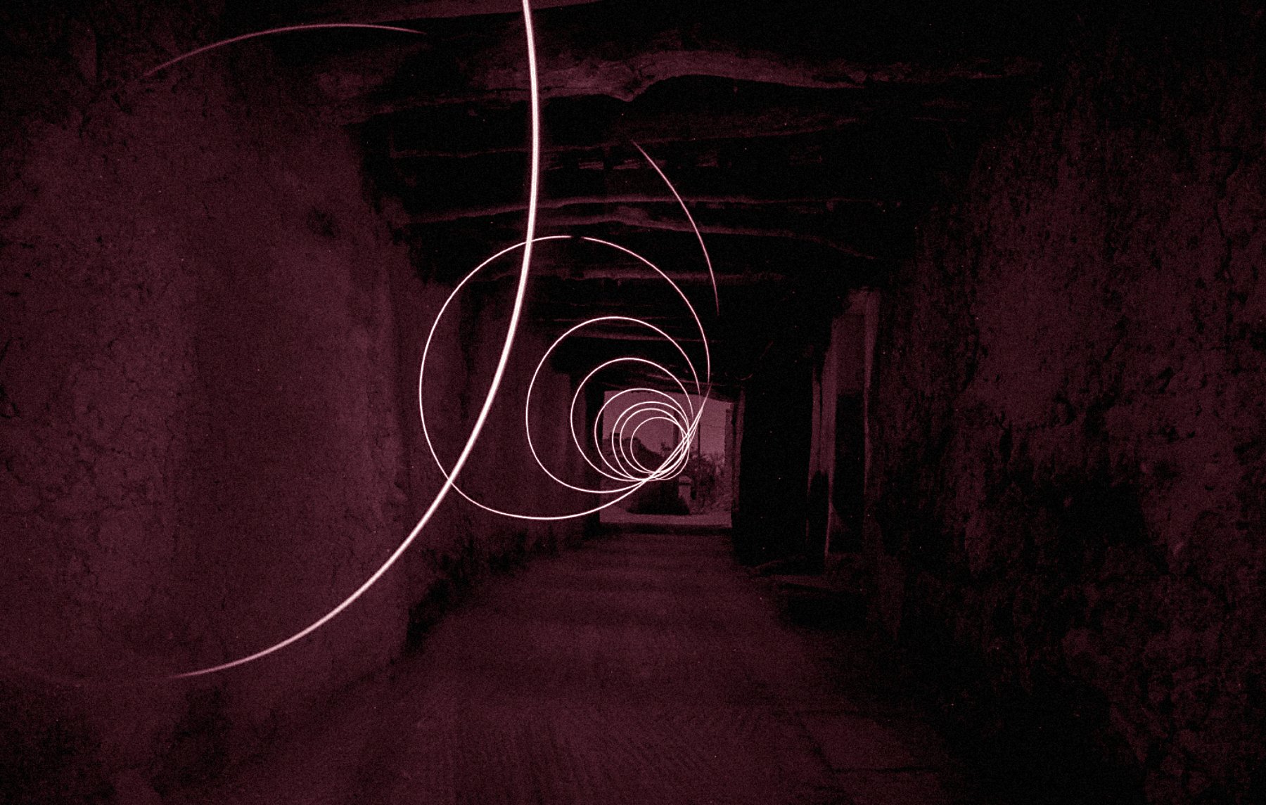 L'image présente un couloir sombre et étroit, avec des murs en pierre, qui semble s'étendre à l'infini. Des spirales lumineuses de couleur rose flottent dans l'air, créant une atmosphère mystérieuse et surréaliste. La lumière des spirales se détache sur le fond sombre, ajoutant une dynamique captivante à la composition. Le sol est en pierre, et la structure du plafond est visible, renforçant le sentiment d'un espace ancien ou abandonné.