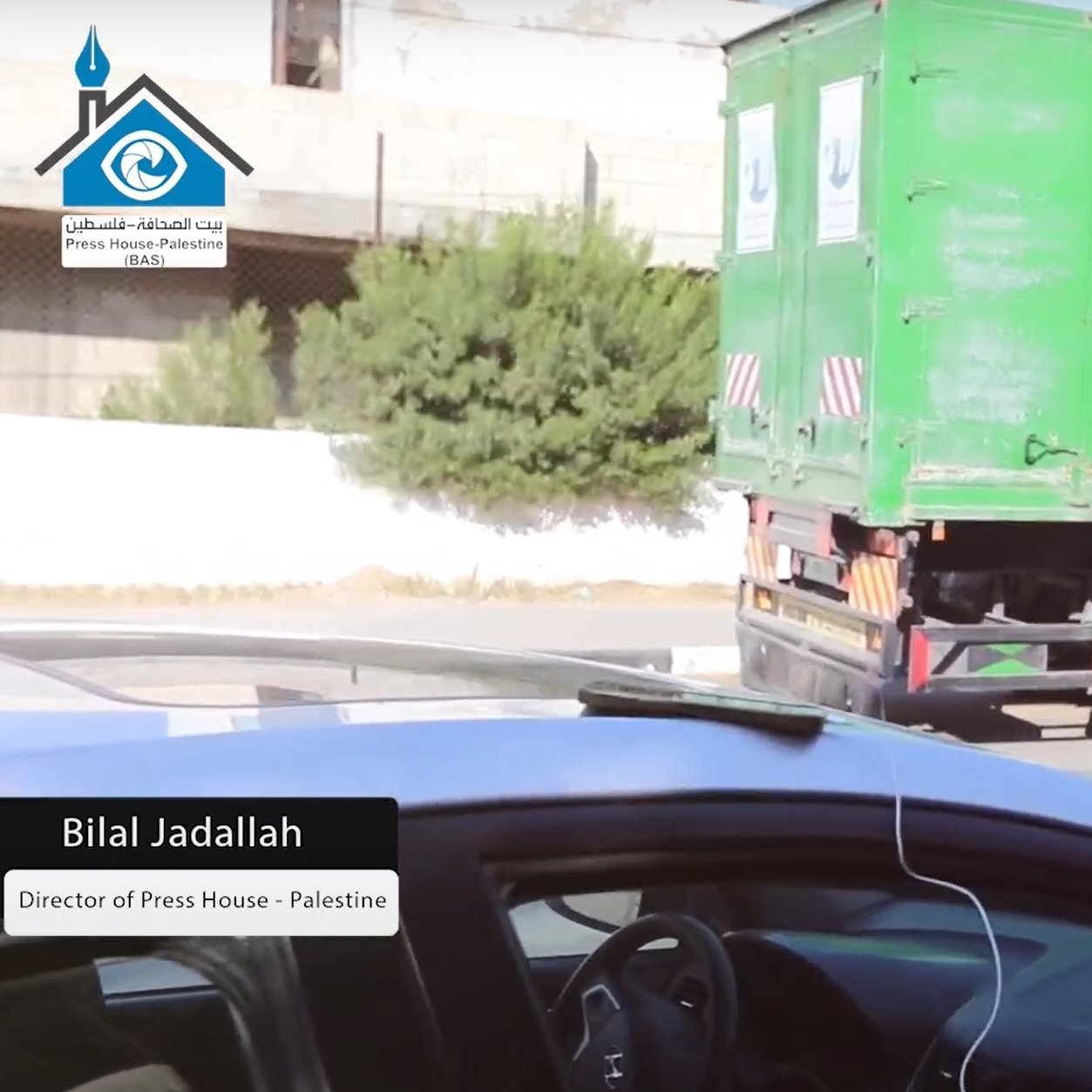 در این تصویر، مردی به نام بیلا الجدلله دیده می‌شود که ظاهراً مدیر خانه مطبوعات در فلسطین است. او در حال حرکت در یک خیابان است و هدفون‌هایی به گوش دارد. در پس‌زمینه یک کامیون سبز رنگ قرار دارد. این تصویر به وضوح زندگی روزمره و فعالیت‌های فردی او را نشان می‌دهد.
