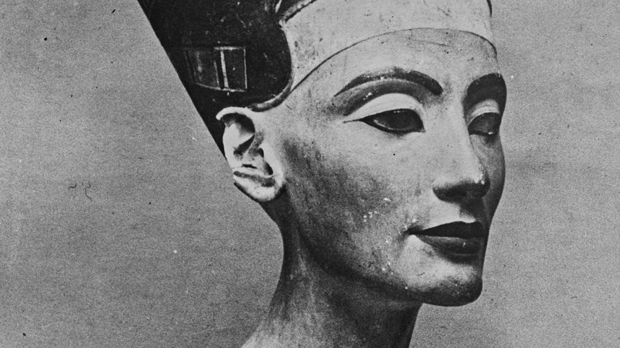 L'immagine rappresenta un busto di pietra di una figura femminile, noto per essere la regina Nefertiti, famosa per la sua bellezza e per il suo ruolo nella storia dell'antico Egitto. Il busto è caratterizzato da un copricapo distintivo e da dettagli elaborati sulla collana e sul viso. La scultura ha un aspetto realistico e raffinato, evidenziando l'arte egizia antica. Il colore della pietra è chiaro con alcune dorature, e l'espressione del volto è serena e dignitosa.