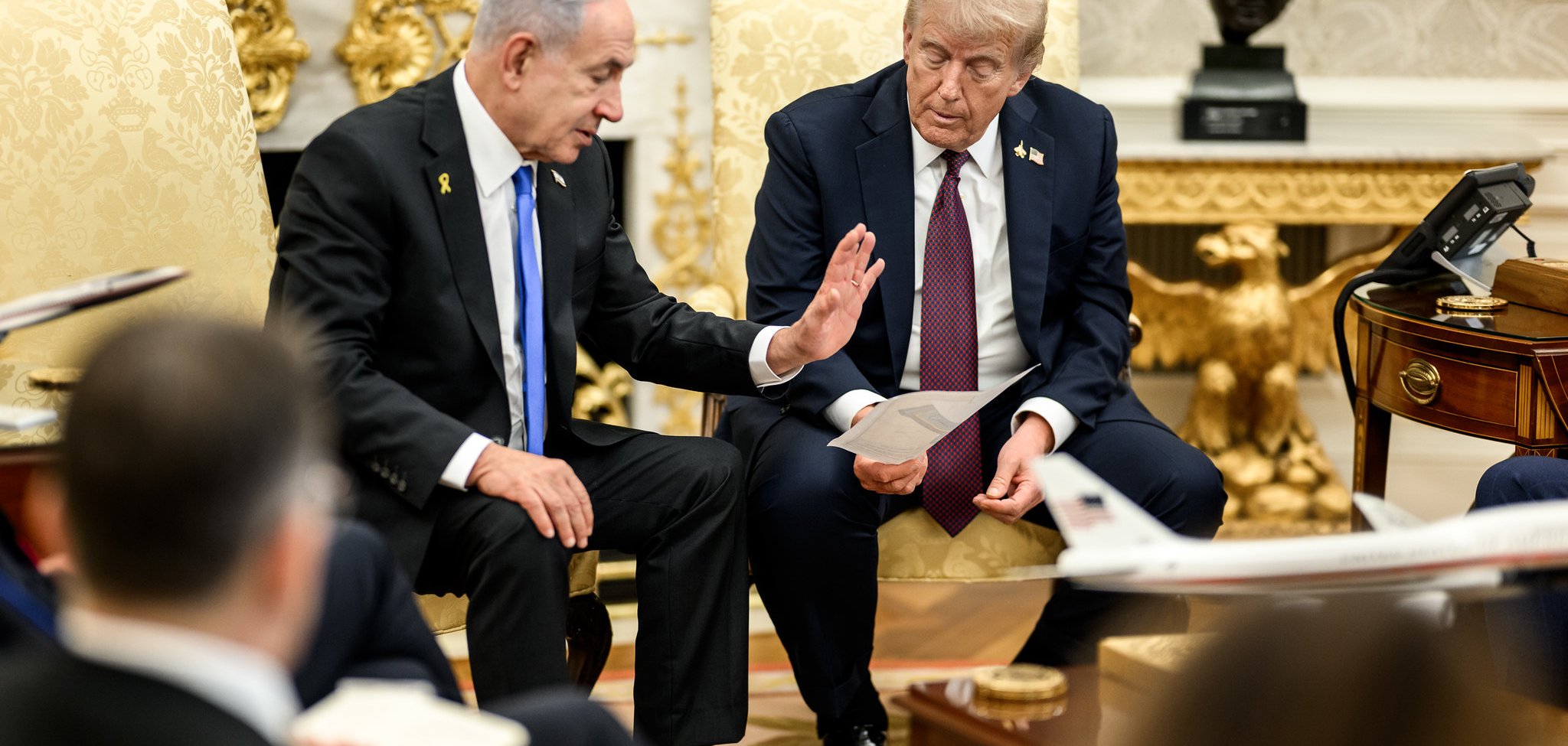 Due uomini in abiti formali discutono seduti su poltrone in un ambiente elegante.