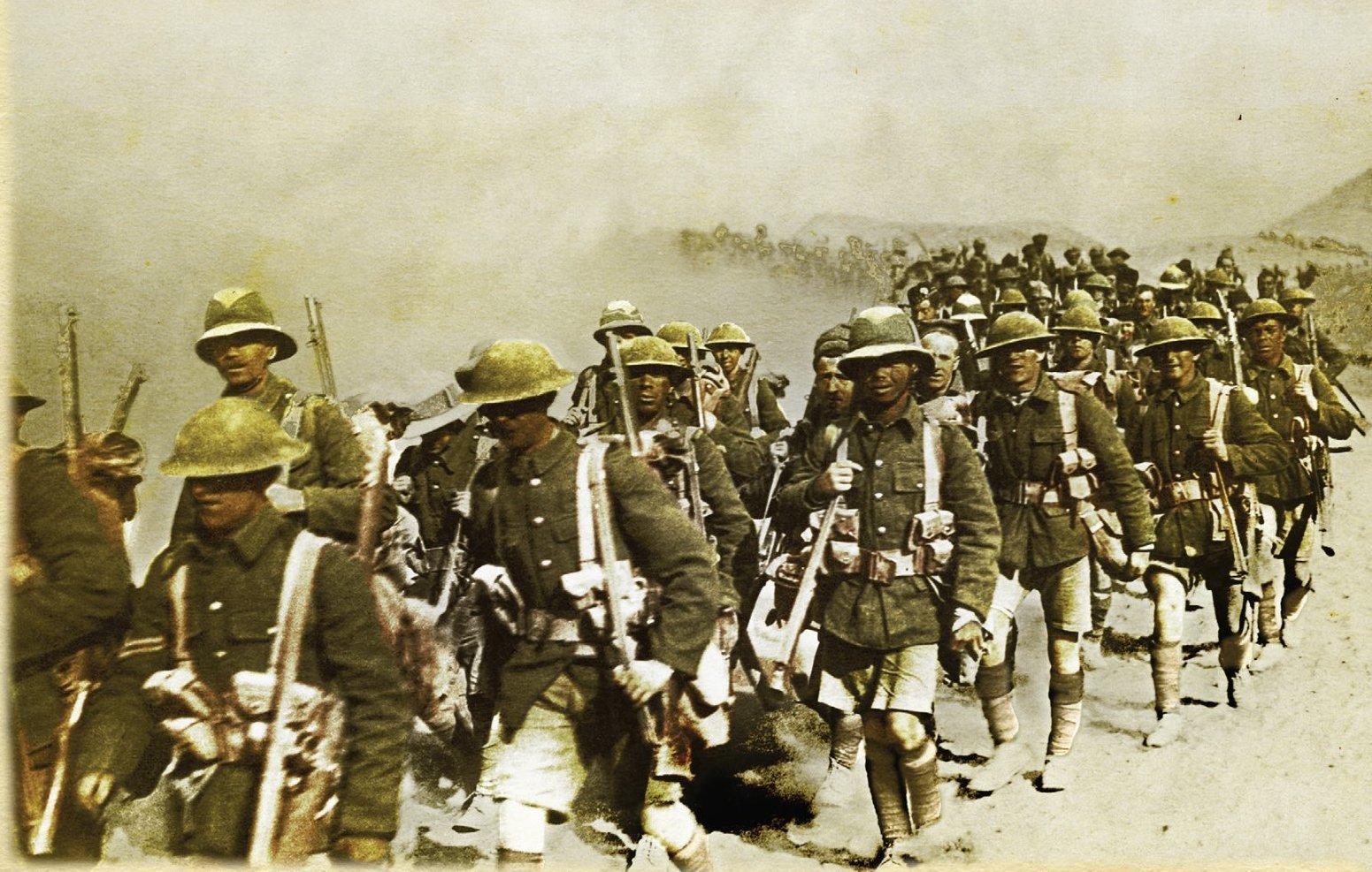L'image représente un groupe de soldats en marche, probablement pendant une période de conflit. Ils portent des uniformes militaires, y compris des casques et des équipements de combat. Les soldats avancent sur un terrain poussiéreux, et il semble qu'ils soient dans un environnement difficile, avec une atmosphère chargée de fumée ou de poussière. L'image donne une impression de détermination et de camaraderie parmi les troupes.