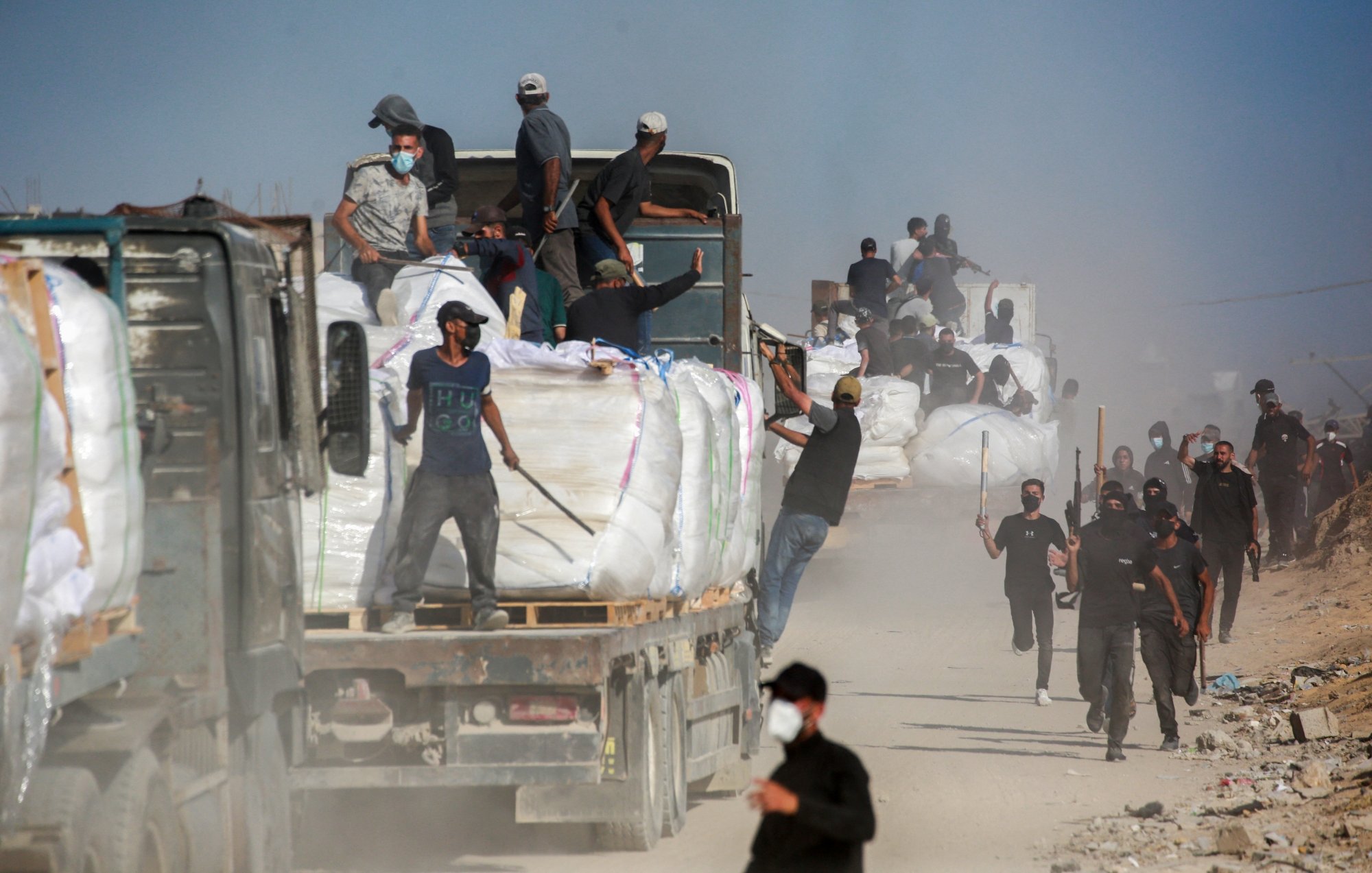 Des camions chargés de marchandises, des travailleurs en mouvement dans la poussière.