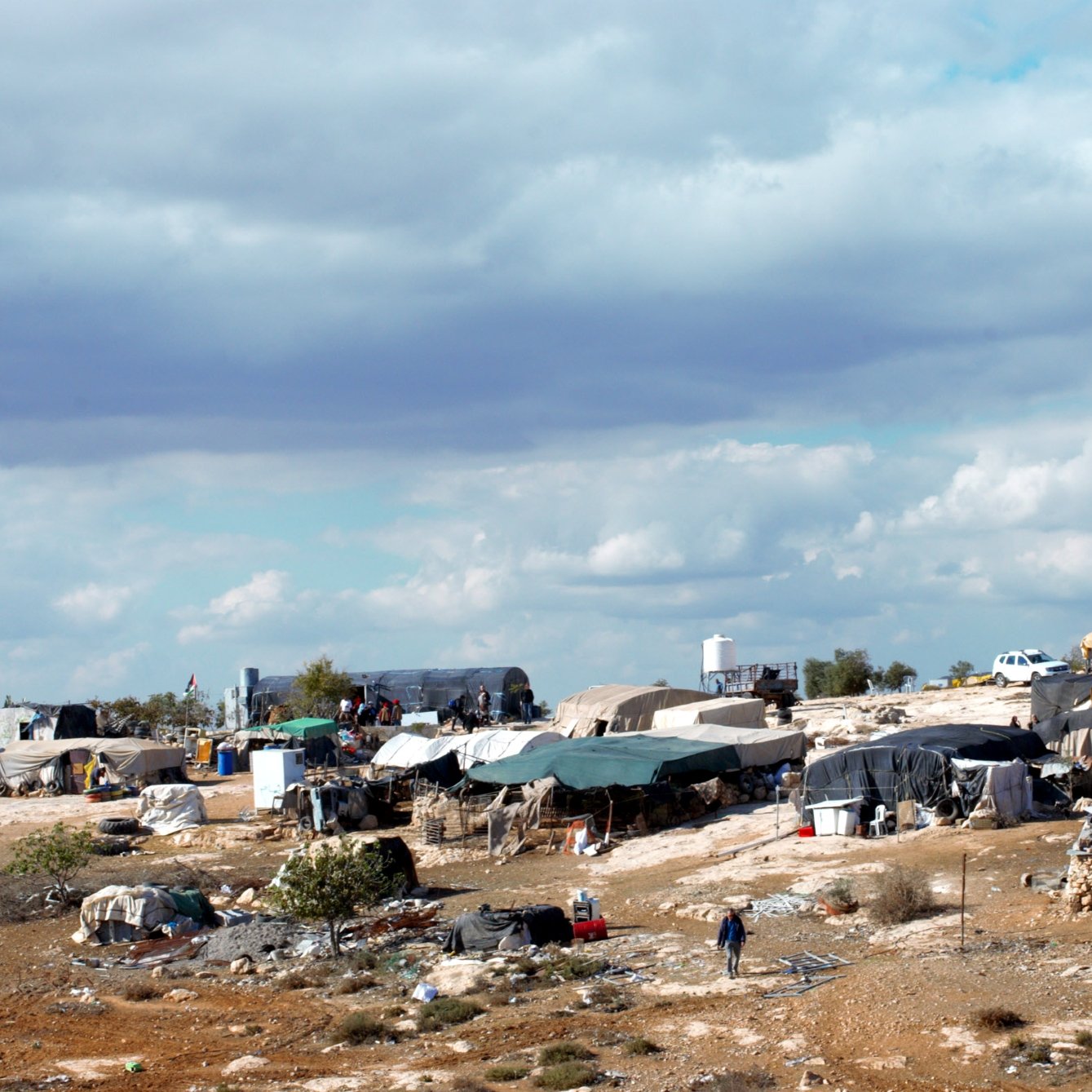 Des tentes éparses sur un terrain rocky, sous un ciel nuageux.