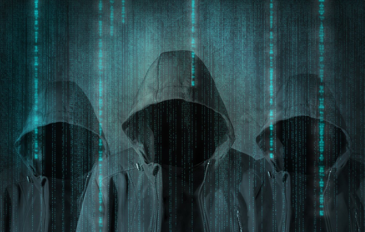 این تصویر نمایی تاریک و دیجیتالی را نشان می‌دهد که در آن سه شخصیت با هودی‌های تیره قرار دارند. چهره‌های آن‌ها نامشخص است و به نظر می‌رسد در پس‌زمینه‌ای پر از خطوط کد و داده‌های دیجیتال قرار دارند. این نمای گویی حس رمزآلودی و فناوری‌های مدرن را منتقل می‌کند، مانند تصاویری که در فیلم‌های سایبرپانک یا مرتبط با هک و دنیای دیجیتال مشاهده می‌شود. رنگ‌های تیره و الگوهای درخشان آبی به شدت توجه را جلب می‌کند.