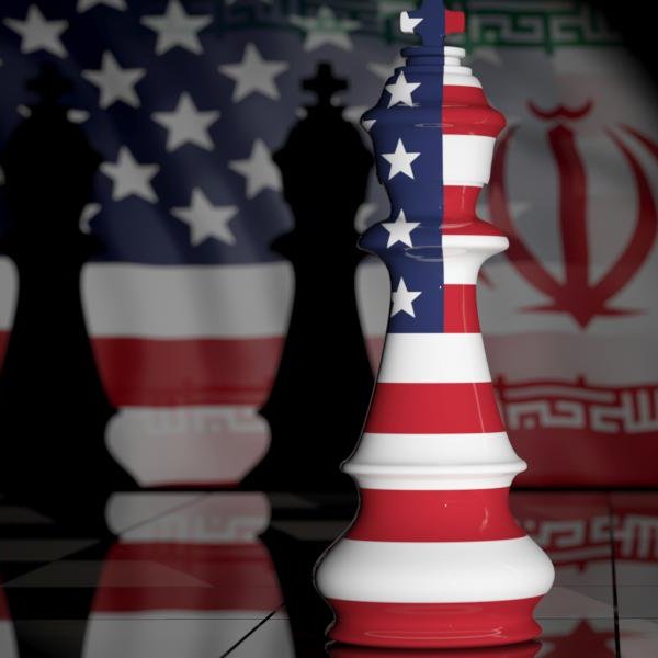 تصویر نشان‌دهنده دو مهره شطرنج است که به نمادهای ملی ایالات متحده و ایران تزئین شده‌اند. مهره سفید به پرچم ایالات متحده و مهره قرمز به پرچم ایران منقش شده است. پس‌زمینه تصویر تاریک و مرموز است و حس رقابت و تضاد بین دو کشور را منتقل می‌کند. زمین شطرنج نیز با الگوی خاصی به تصویر اضافه شده که به فضای بازی شطرنج اشاره دارد.