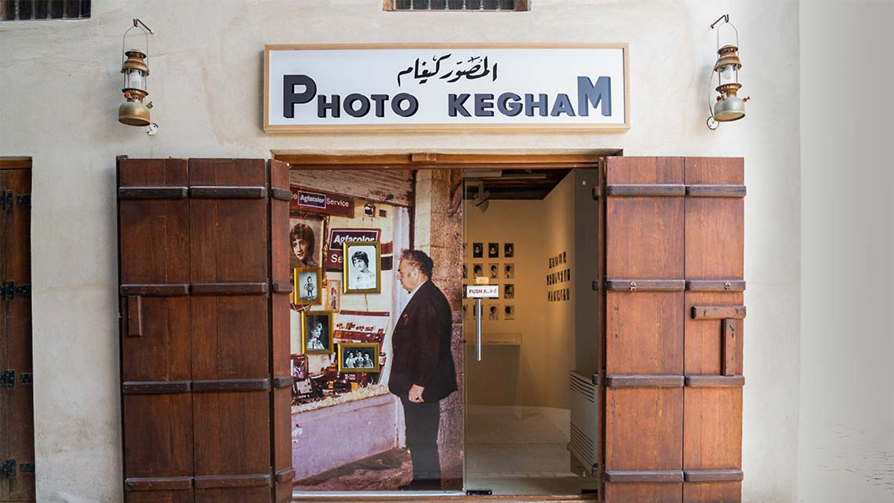 A small photo shop entrance with wooden doors, showcasing images and an exhibit inside.