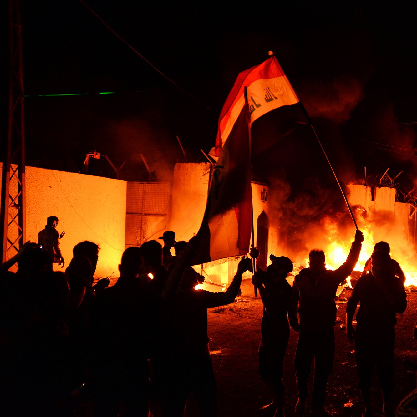 در این تصویر، گروهی از مردم در بامداد، در حال برپایی تظاهرات یا اعتراض هستند. آن‌ها در دست‌ها پرچم عراق را بلند کرده‌اند و در پس‌زمینه، آتش‌سوزی‌هایی در حال ایجاد است که موجب ایجاد نور و دود در فضا شده است. صحنه جوش و خروش و هیجان را نشان می‌دهد و احساسات قوی معترضان را به تصویر می‌کشد. دیوارهایی در اطراف دیده می‌شود که ممكن است بخشی از یک ساختمان یا منطقه محصور باشد.