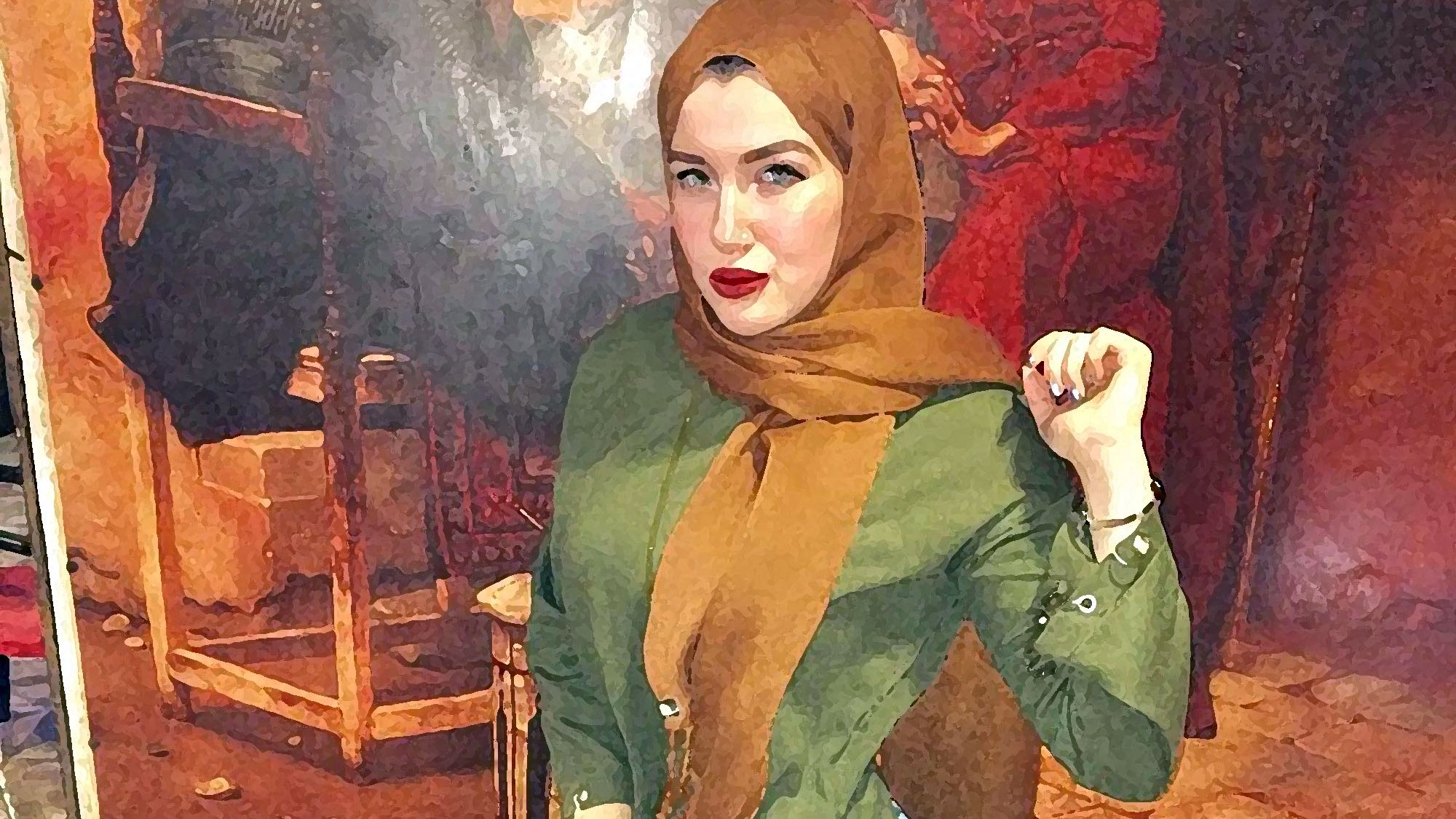 L'immagine mostra una giovane donna che indossa un hijab color marrone e una camicia verde. È in piedi con una mano sulla vita e l'altra sollevata, con un'espressione sicura. Indossa jeans attillati e scarpe marroni. Sullo sfondo si intravede un dipinto o una decorazione murale che aggiunge un tocco di colore all'ambiente. L'illuminazione sembra calda, contribuendo a un'atmosfera accogliente.