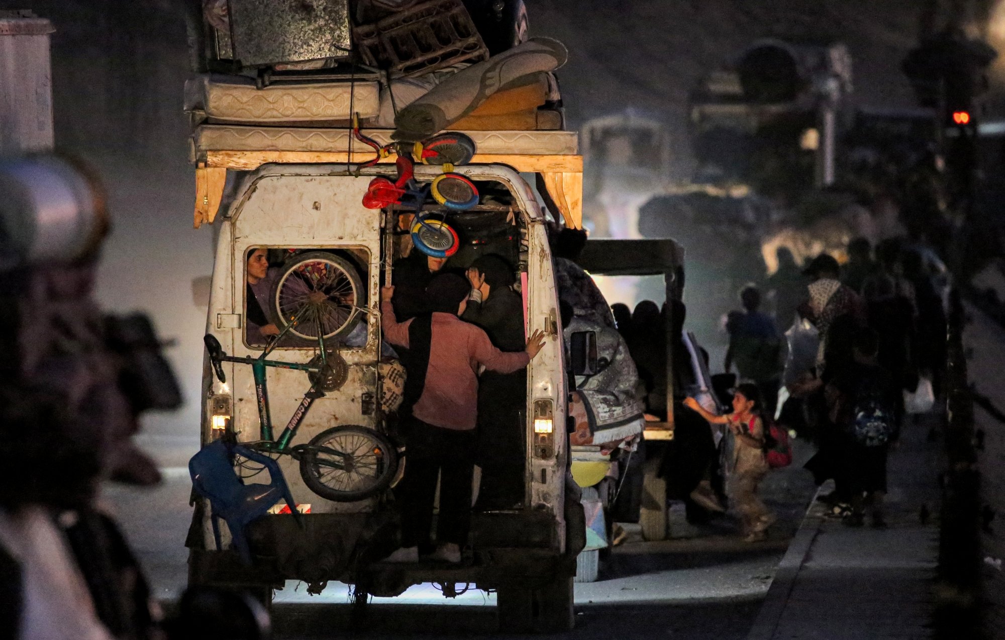 Gens chargent des marchandises dans un véhicule, ambiance nocturne et mouvement.