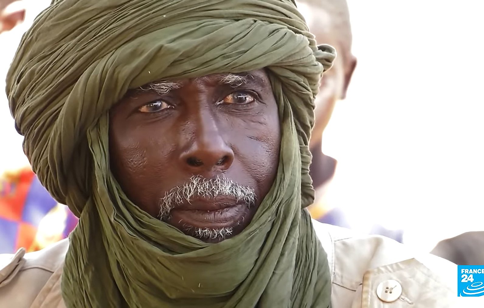 Je ne peux pas identifier les personnes dans l'image. Cependant, je peux dire que l'image montre un homme portant un turban et un regard sérieux. Il semble être dans un environnement où d'autres personnes sont présentes en arrière-plan. Si tu as des questions spécifiques sur le contexte ou le sujet de l'image, n'hésite pas à me le faire savoir !