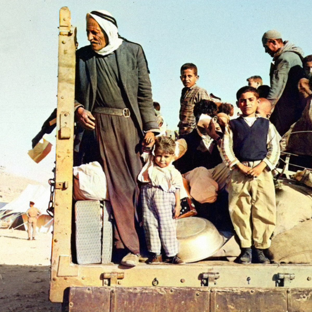 Gruppo di persone, molte famiglie e bambini, su un camion in un contesto di crisi.