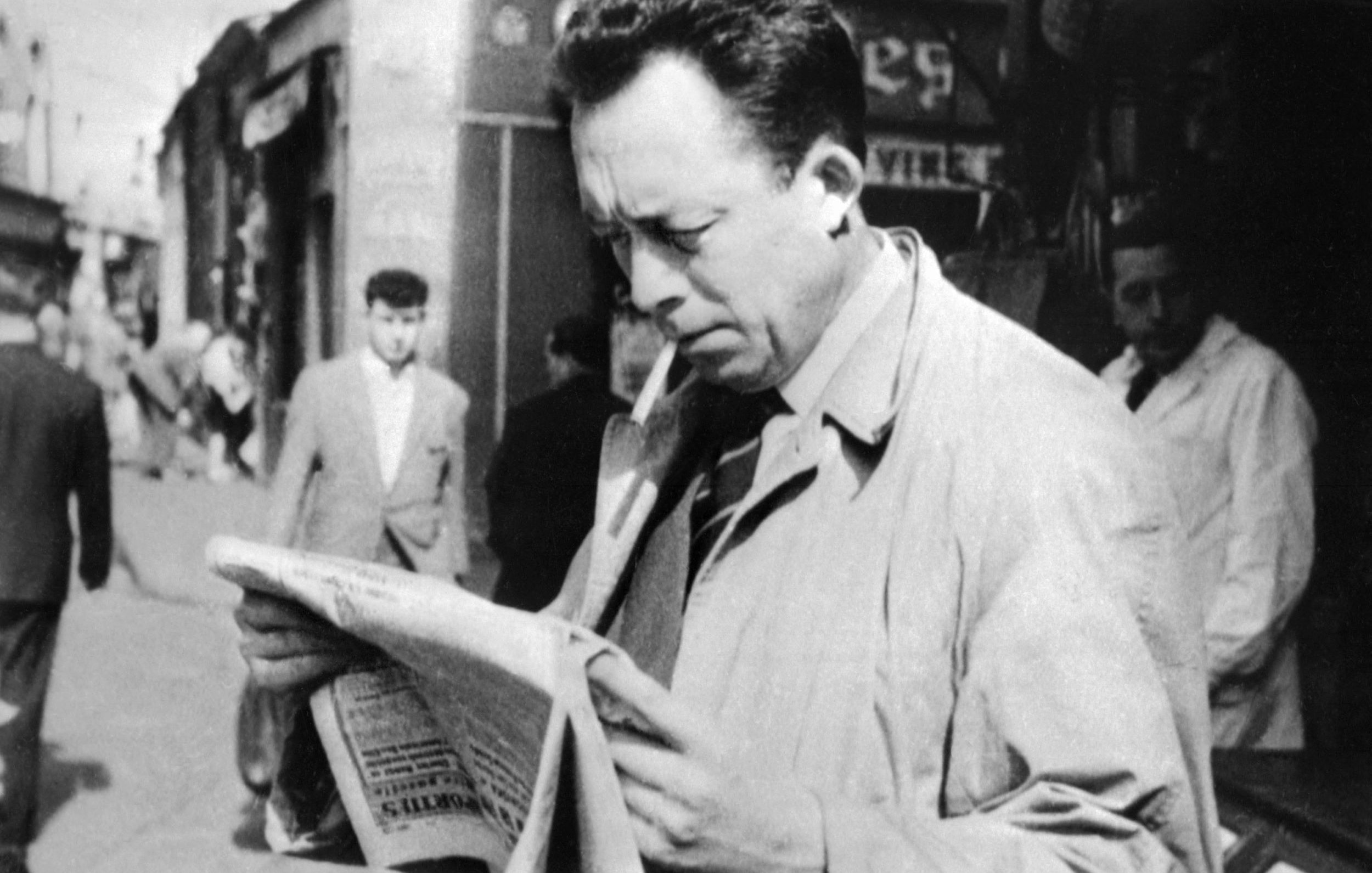 L'image représente un homme dans une rue animée, semblant lire un journal avec attention. Il porte un manteau clair et une cigarette à la bouche. En arrière-plan, on peut voir d'autres passants et des commerces, ce qui donne une ambiance des années passées. La scène évoque une atmosphère de réflexion et d'intérêt pour l'actualité.