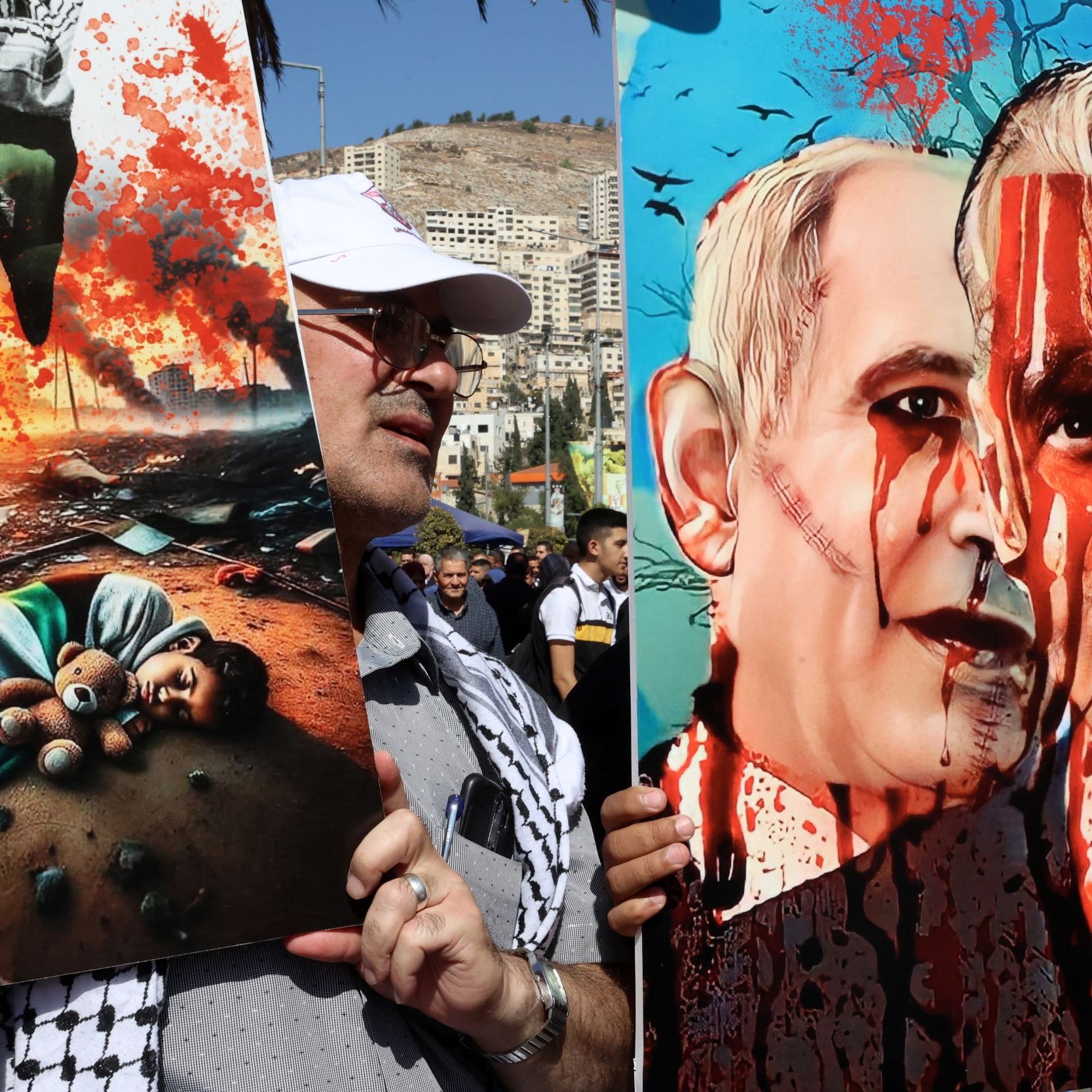 La imagen muestra a un manifestante sosteniendo dos carteles. En el cartel de la izquierda, hay una ilustración impactante que representa un ambiente devastado, con un niño tirado en el suelo, y elementos que sugieren destrucción y sufrimiento. El cartel de la derecha presenta retratos de dos figuras, probablemente con un contexto político, mostrando rostros con sangre, lo que sugiere un mensaje fuerte y crítico sobre la violencia o el conflicto. Ambos carteles reflejan una expresión poderosa de protesta.