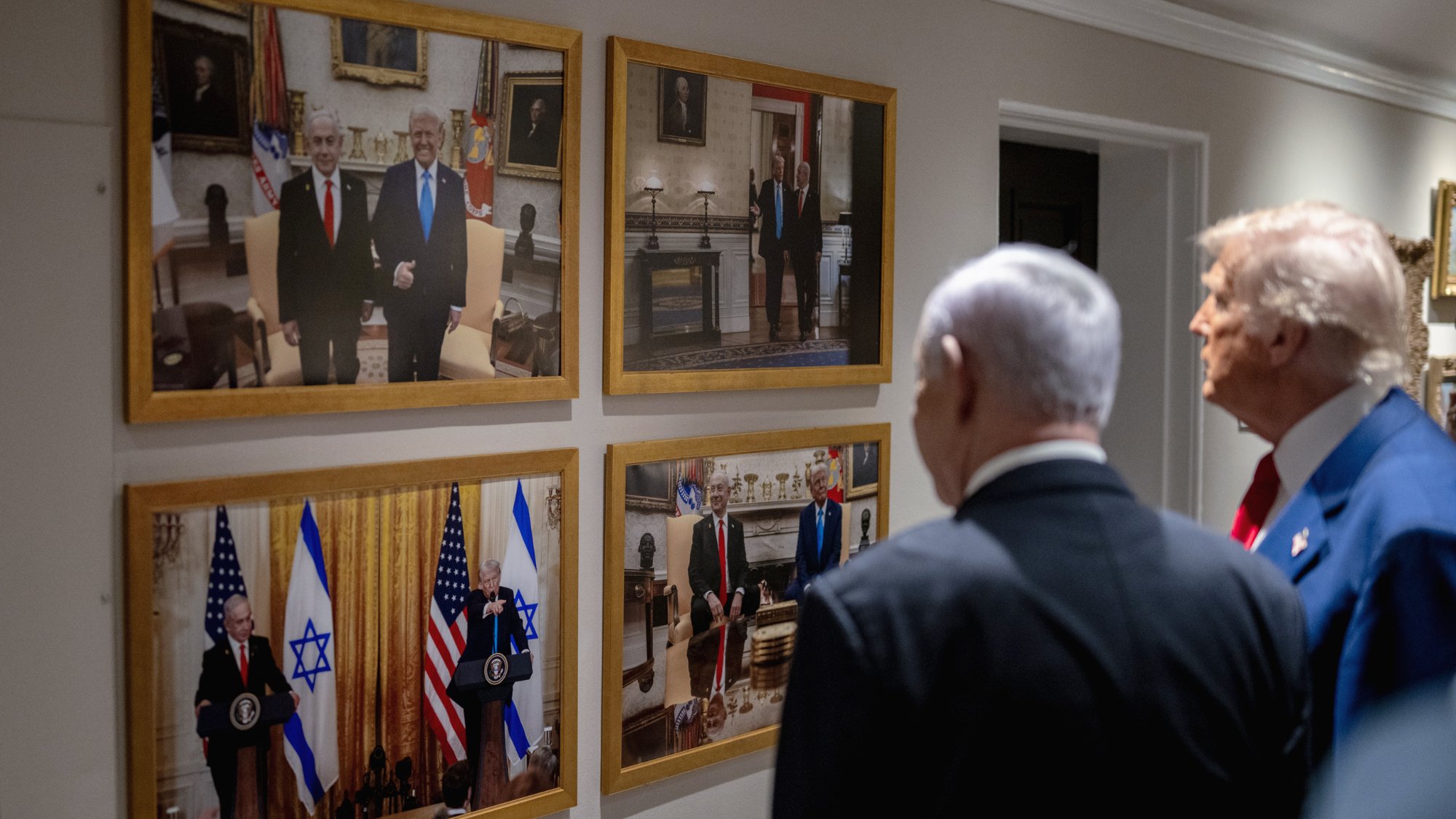 Des hommes politiques regardent des photos accrochées au mur, représentant des rencontres officielles.