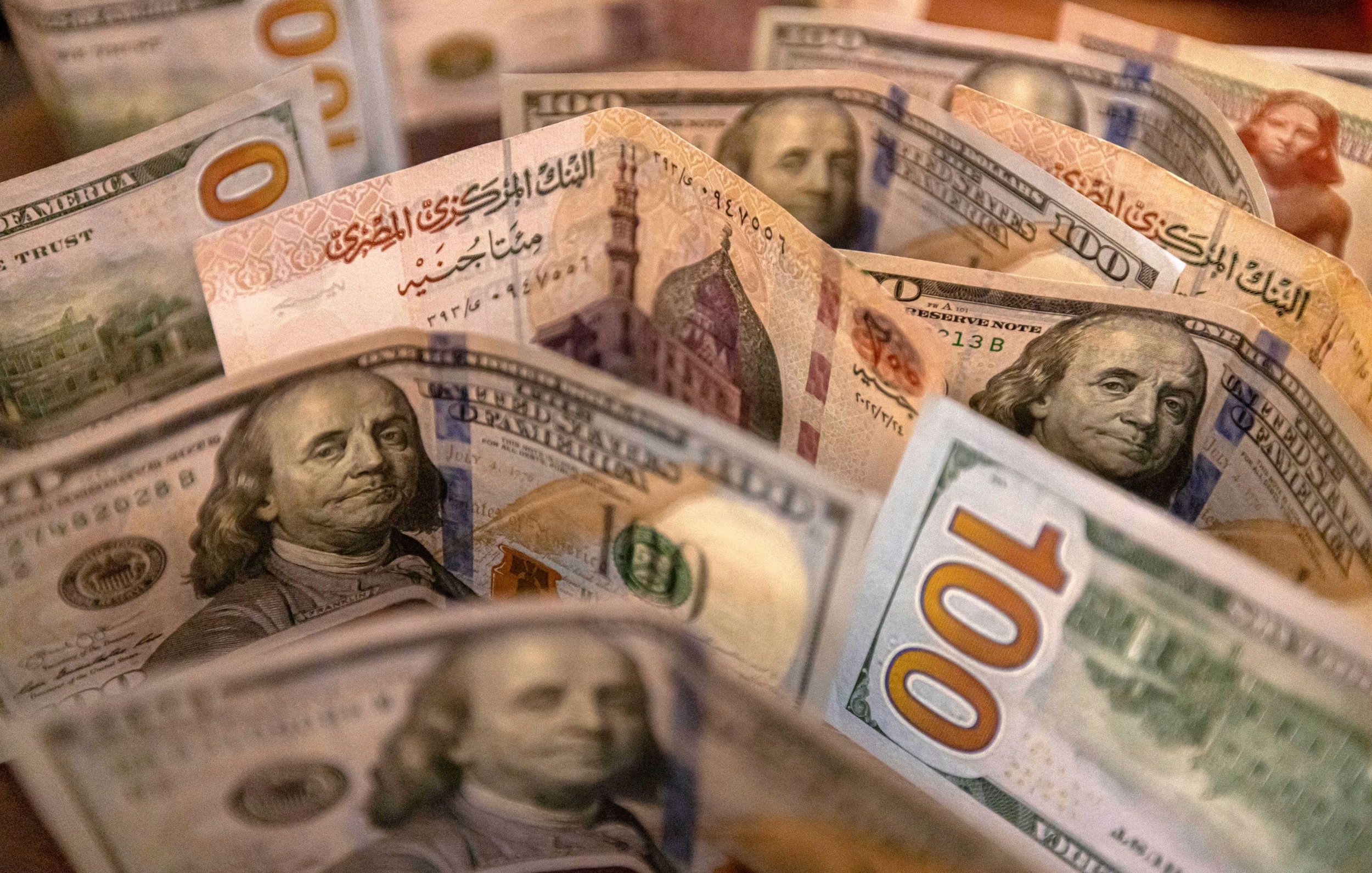 L'image montre un assortiment de billets de banque, probablement des dollars américains. On peut voir plusieurs billets de 100 dollars, avec des illustrations de Benjamin Franklin, ainsi que d'autres détails de la conception des billets. Les billets sont disposés de manière à créer une sorte de fan, mettant en évidence les différentes couleurs et motifs.