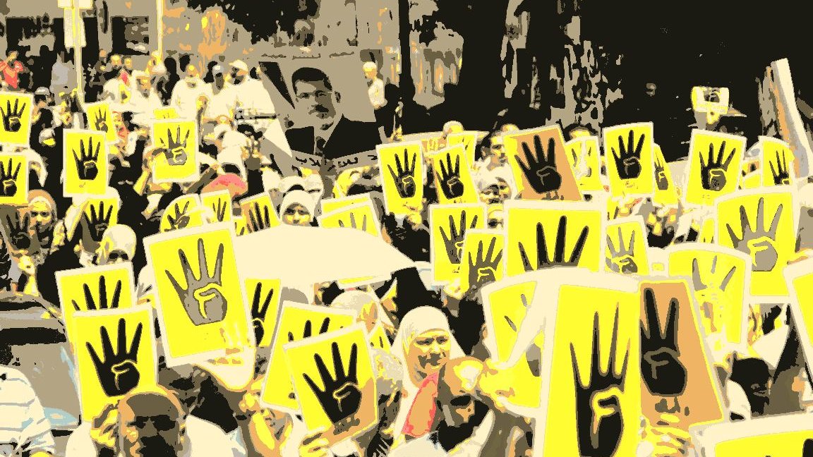 L'image montre une grande manifestation avec de nombreuses personnes rassemblées. Elles tiennent des panneaux jaunes avec un symbole représentant une main levée, souvent associée à des mouvements de protestation. Les participants sont majoritairement habillés en vêtements clairs. En arrière-plan, on peut voir des arbres et des bâtiments, ce qui suggère que la manifestation se déroule en milieu urbain. L'atmosphère semble être à la fois déterminée et engagée, avec un fort esprit de solidarité parmi les manifestants.