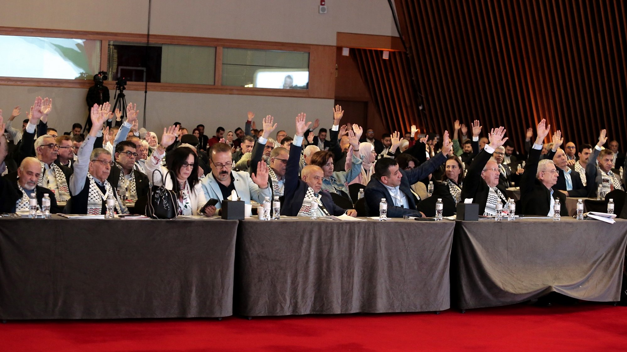 Salle de réunion avec des participants levant la main pour voter.