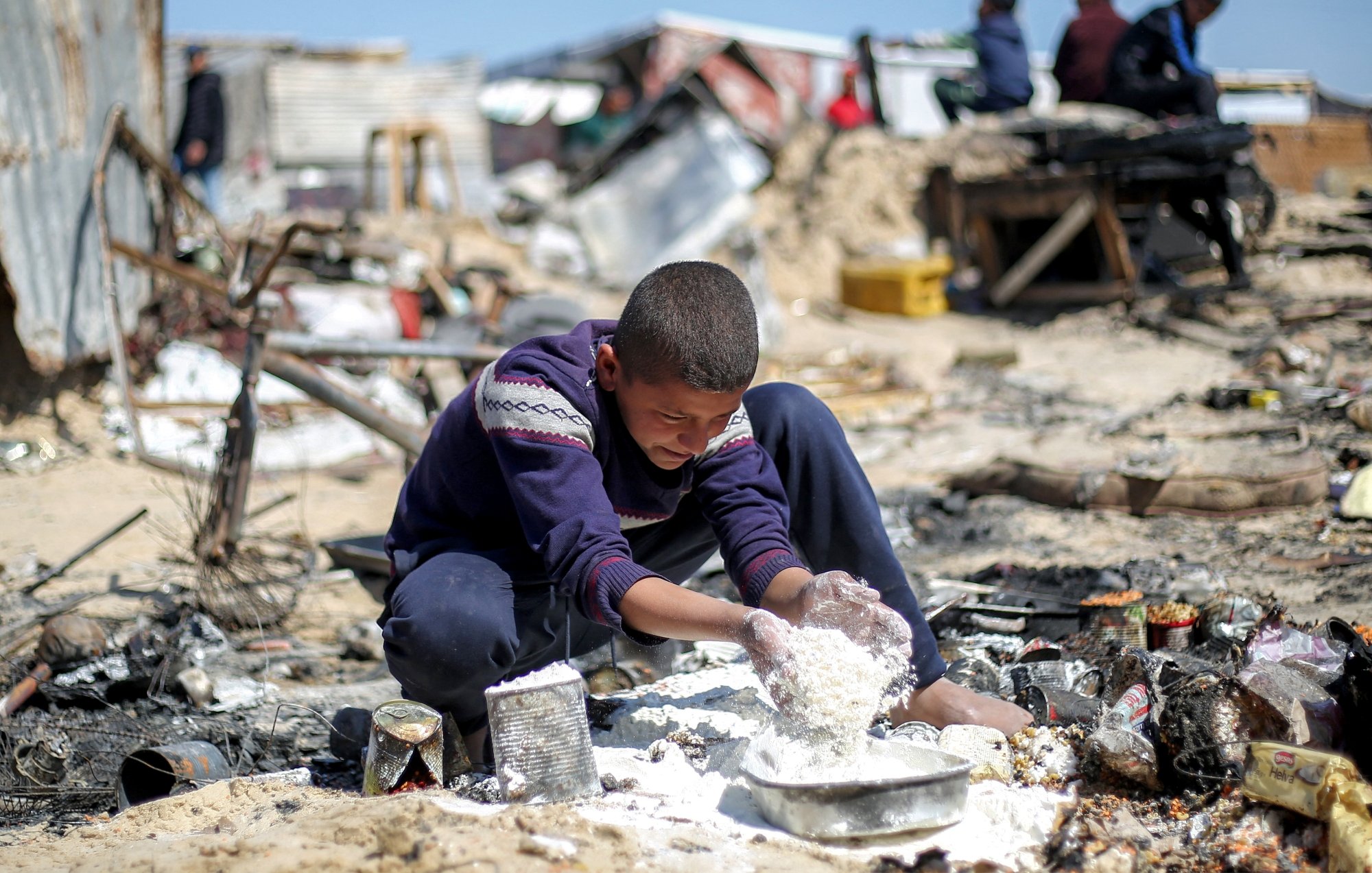 Un garçon joue dans un environnement désordonné, entouré de débris et de ruines.