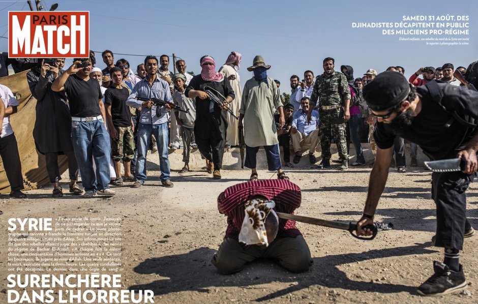 L'image semble représenter une scène dramatique dans un contexte de conflit. Elle montre un groupe de personnes, probablement dans un environnement de guerre, où des individus armés sont présents. Au premier plan, une personne est à genoux, apparemment soumise à des actes de violence, entourée par d'autres qui semblent observer la situation. L'atmosphère est tendue et illustre des thèmes de violence et de conflit, mettant en évidence des tensions entre différentes factions. Les éléments de l'image témoignent d'un contexte difficile et tragique.