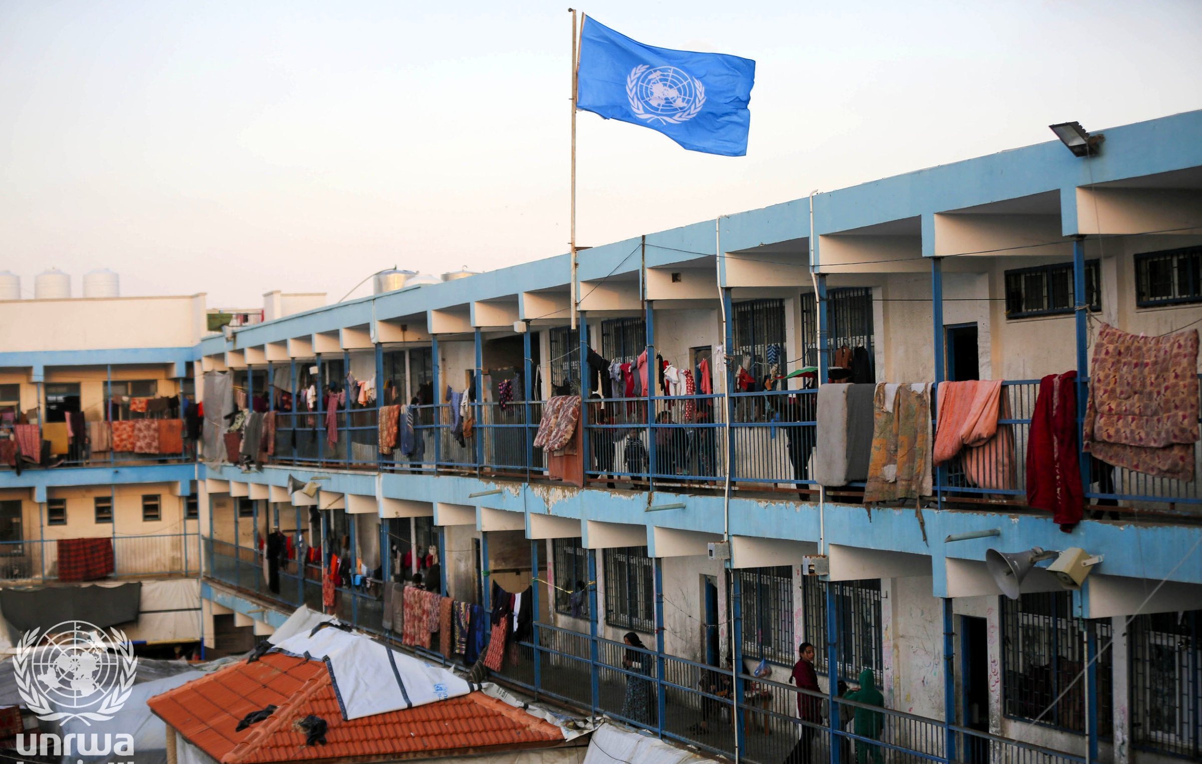 Un edificio con balconi allineati, bandiera ONU e vestiti appesi ad asciugare.