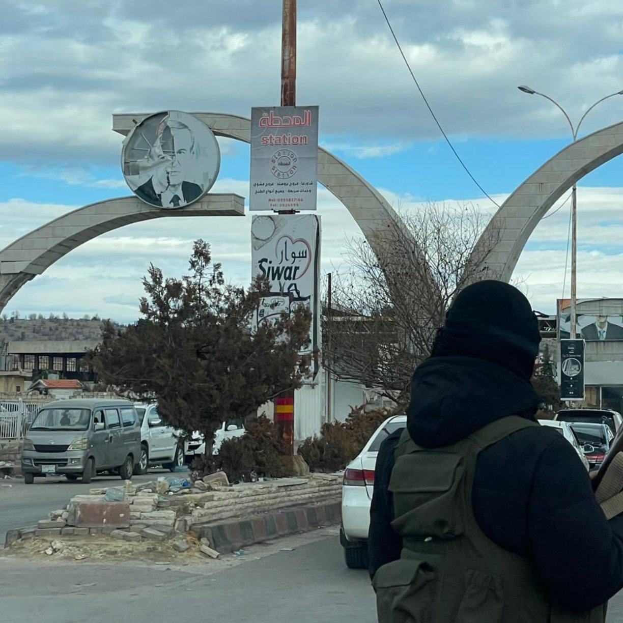 صورة لبوابة كبيرة تتوسطها أعمدة، وأجواء حضرية مزدحمة بالسيارات والمارة.