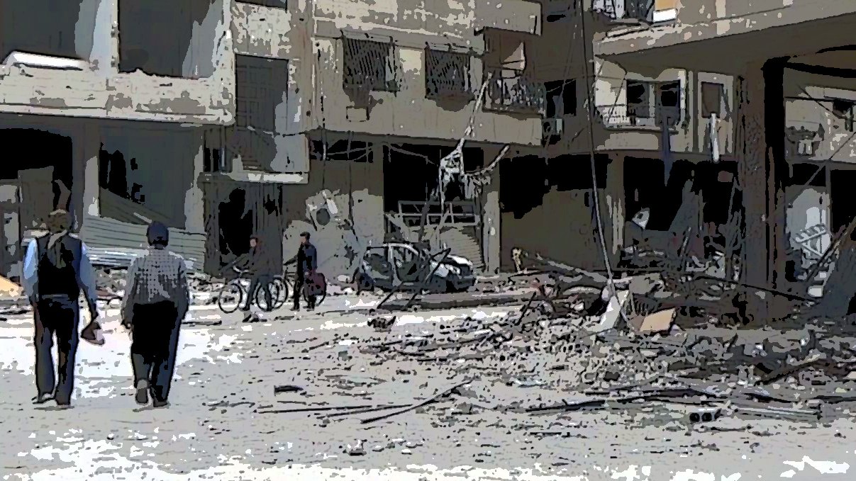 L'image montre une scène de destruction dans une zone urbaine. On y voit des bâtiments endommagés, avec des débris éparpillés sur le sol. Deux personnes marchent au premier plan, tandis que d'autres personnes sont visibles au loin, certaines semblent conduire des vélos. L'ambiance générale est triste et chaotique, illustrant les conséquences dévastatrices d'un conflit.