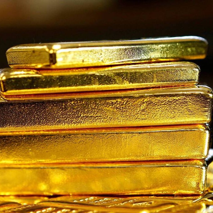 تظهر الصورة مجموعة من قضبان الذهب اللامعة، موضوعة بشكل متراص. القضبان ذات لون ذهبي براق، وتتميز بسطحها الأملس واللامع. يبدو أن القضبان ذات أحجام مختلفة، حيث تم ترتيبها بشكل عمودي، مما يبرز جمال الذهب وقيمته. يحيط بالصورة خلفية ضبابية وغير واضحة، ما يركز الانتباه على القضبان الذهبية.