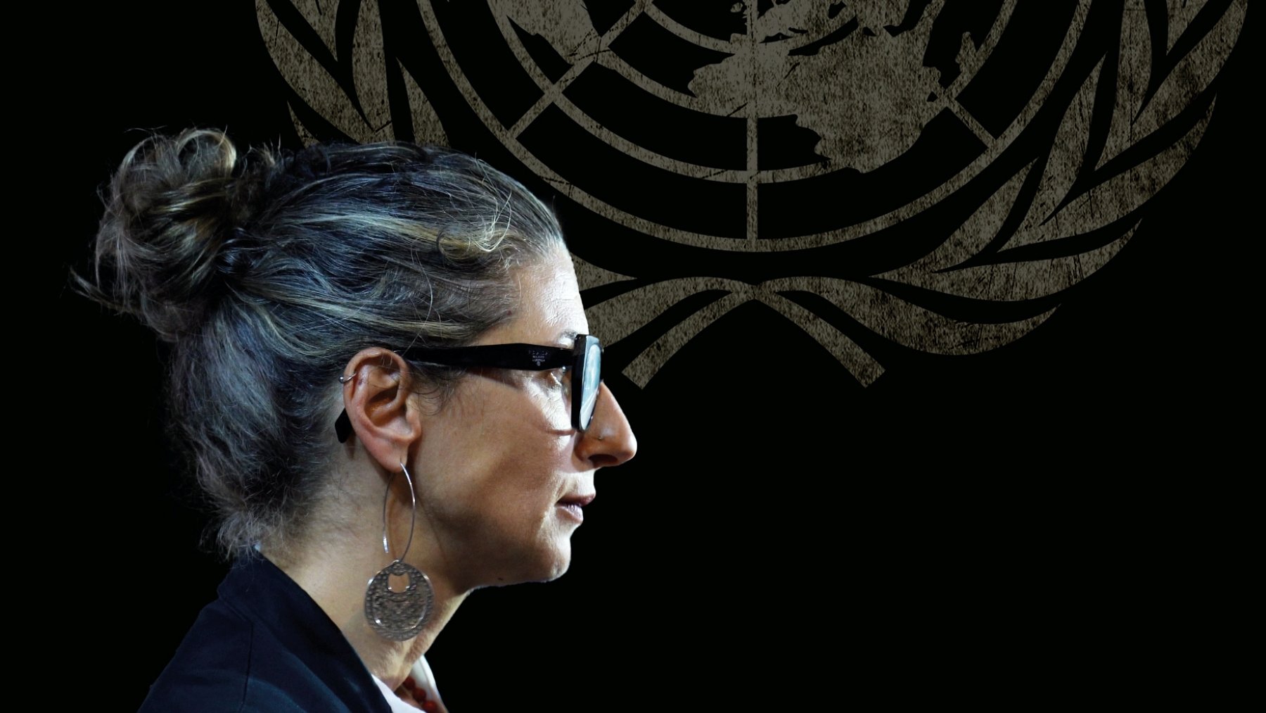 Femme avec des lunettes, coiffure en chignon, silhouette sur fond du logo de l'ONU.