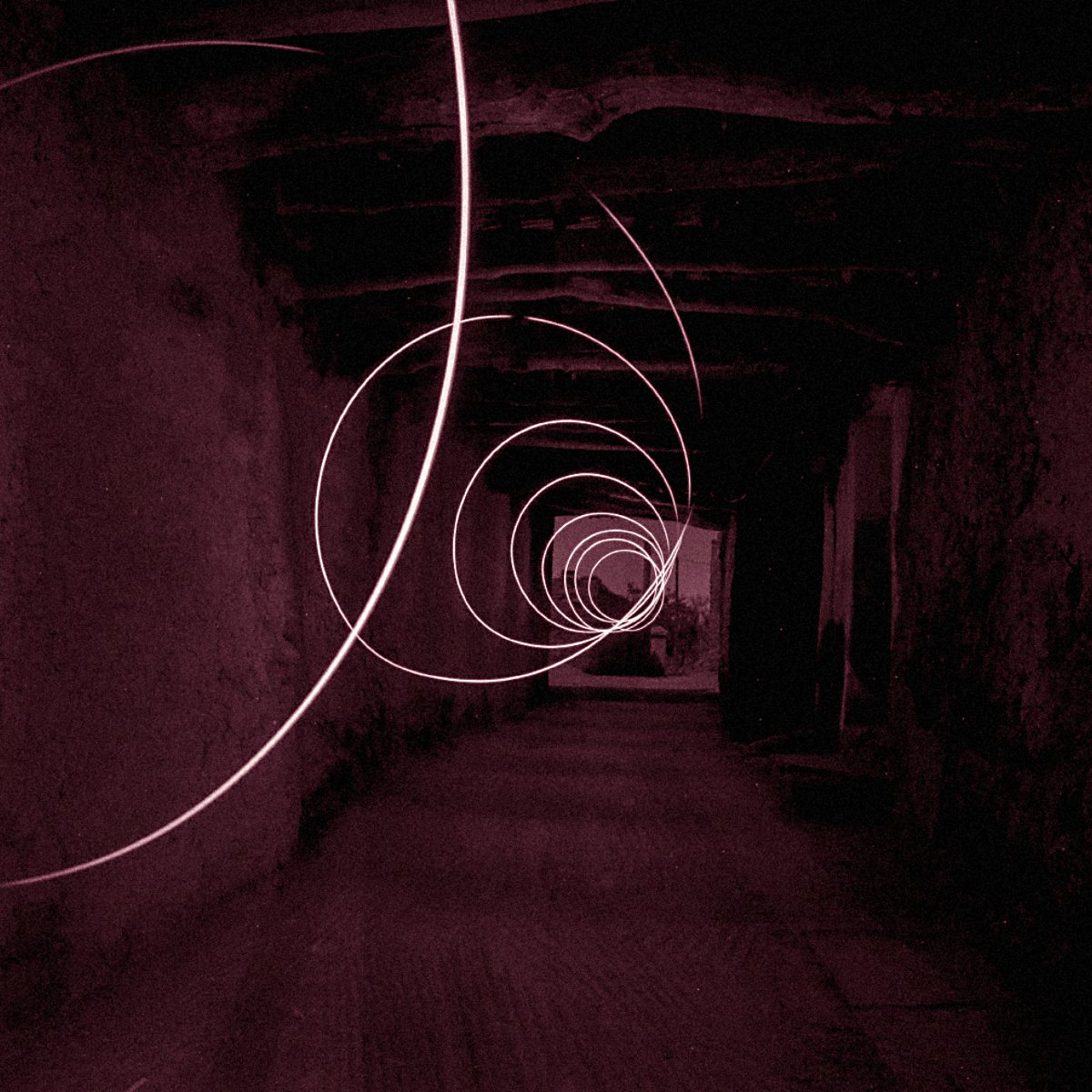 The image depicts a long, seemingly dark corridor with a series of swirling light trails creating a spiral effect. The color tone is predominantly red, contributing to a mysterious and somewhat surreal atmosphere. The walls of the corridor appear rough and textured, enhancing the sense of depth and perspective as the light trails guide the eye towards the far end of the hallway. The overall composition evokes a feeling of motion and intrigue.