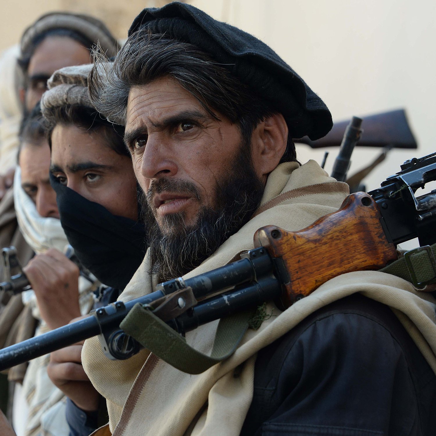 این تصویر گروهی از مردان مسلح را نشان می‌دهد که در یک وضعیت آماده‌باش قرار دارند. آنها لباس‌های سنتی دارند و بعضی از آن‌ها صورت خود را با پارچه پوشانده‌اند. سلاح‌هایشان بر دوششان قرار دارد و تمرکز و جدیت آن‌ها در چهره‌شان مشهود است. زمینه فقط به صورت محو دیده می‌شود و توجه بیشتر به افراد معطوف است.