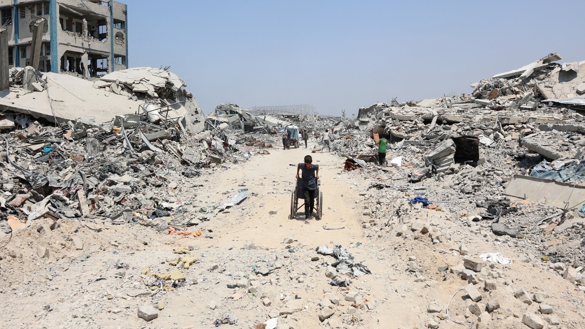 Un chemin au milieu des ruines, une personne en fauteuil roulant avance lentement.