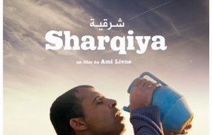L'image représente une scène d'un film intitulé "Sharqiya", réalisé par Ami Livne. On y voit un homme portant un pot en plastique, semblant s'hydrater en plein air. Le décor suggère un paysage rural, avec quelques animaux en arrière-plan. L'expression de l'homme pourrait évoquer une recherche de répit ou un moment de pause dans un environnement quotidien.