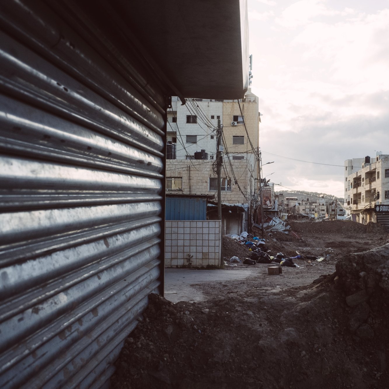 Strade deserte con edifici e terreni in costruzione, atmosfera grigia e cupa.