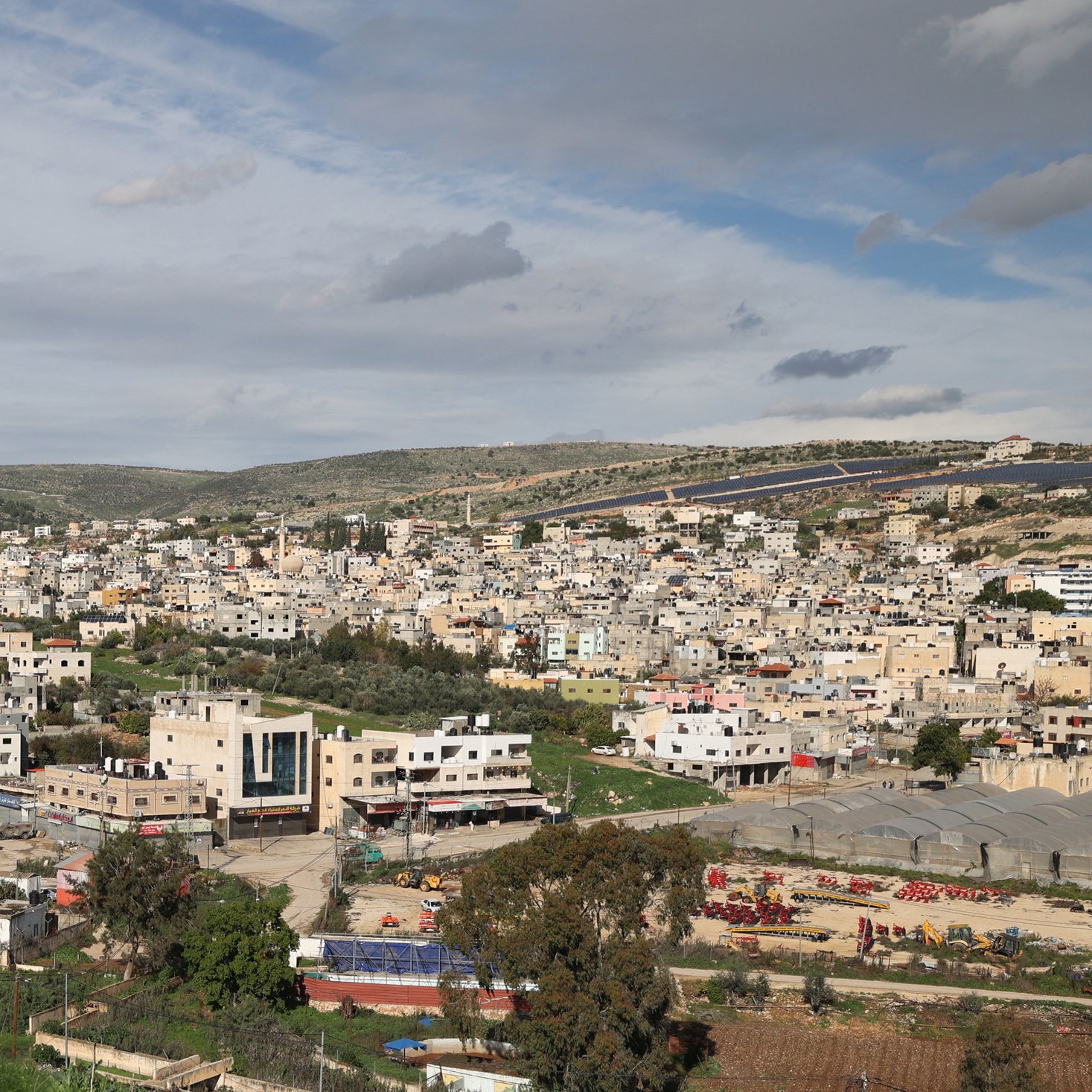 در این تصویر، فردی در حال بالا رفتن یا حرکت در مکانی کوهستانی دیده می‌شود. او لباس‌های غیررسمی به تن دارد و در پس‌زمینه، یک شهر بزرگ با ساختمان‌های مختلف و معماری متنوع دیده می‌شود. آسمان ابری است و مناظر طبیعی اطراف، مانند تپه‌ها و درختان، نیز در تصویر قابل مشاهده‌اند. این صحنه ترکیبی از زندگی شهری و طبیعت را نشان می‌دهد.