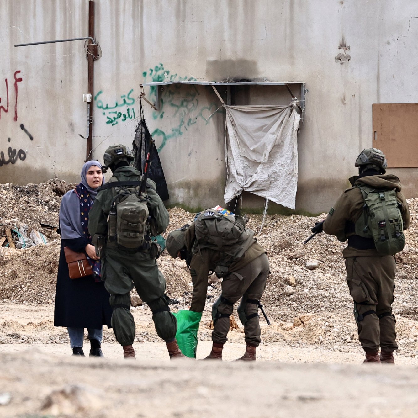 Soldiers in military gear interact with a woman in an urban setting, surrounded by debris.