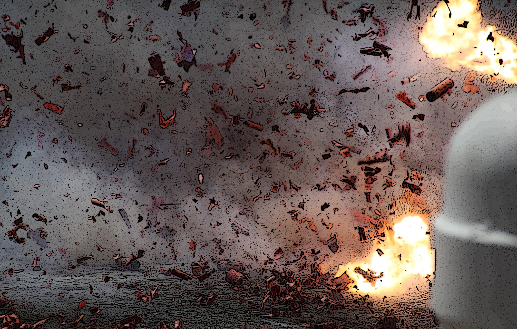 The image depicts an intense explosion, with fragments and debris scattered throughout the scene. There are bright flashes of light indicating the force of the blast, and the background appears smoky and chaotic, suggesting a highly energetic event. The overall atmosphere conveys a sense of destruction and turmoil.