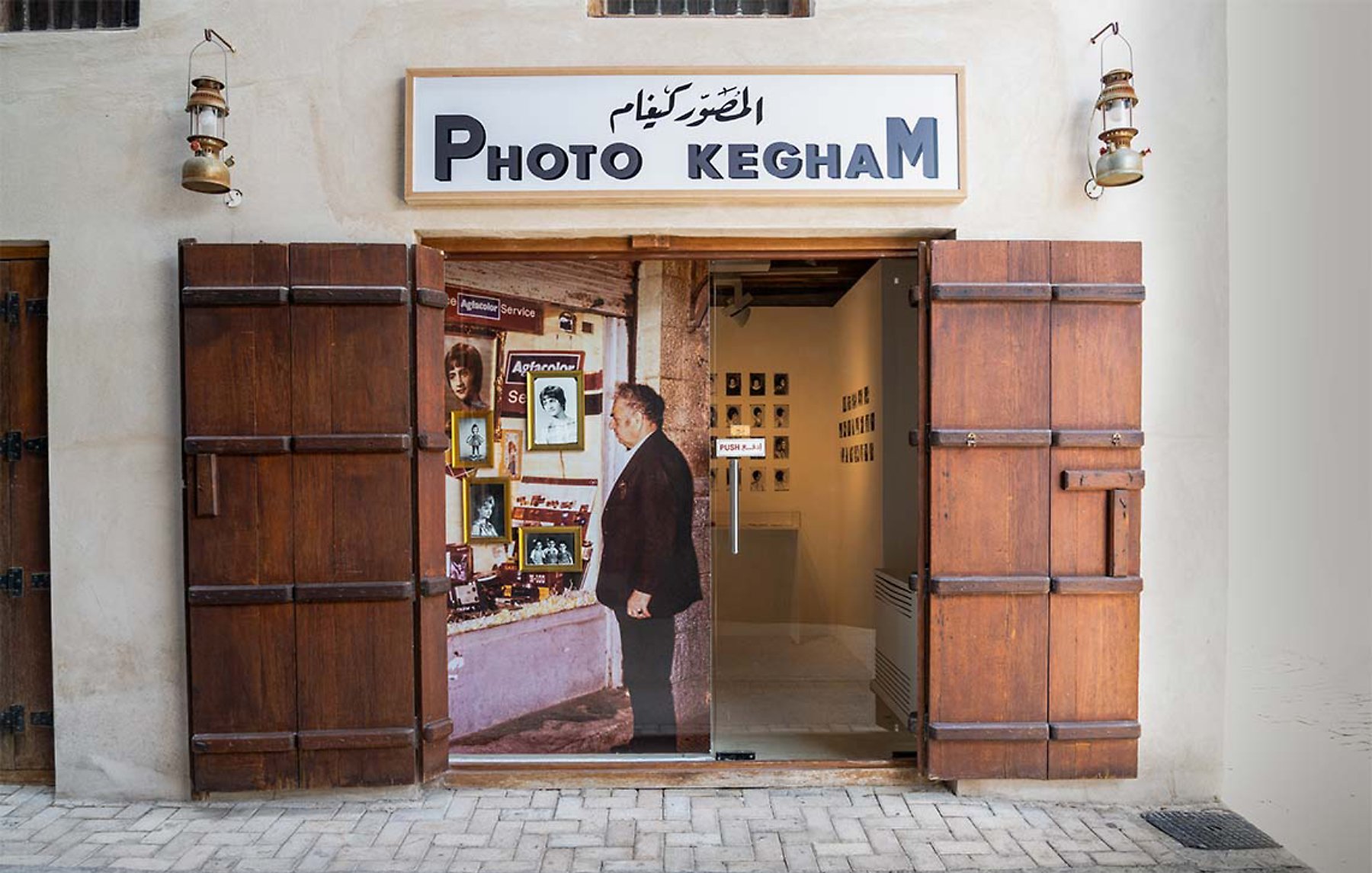 A small photo shop entrance with wooden doors, showcasing images and an exhibit inside.