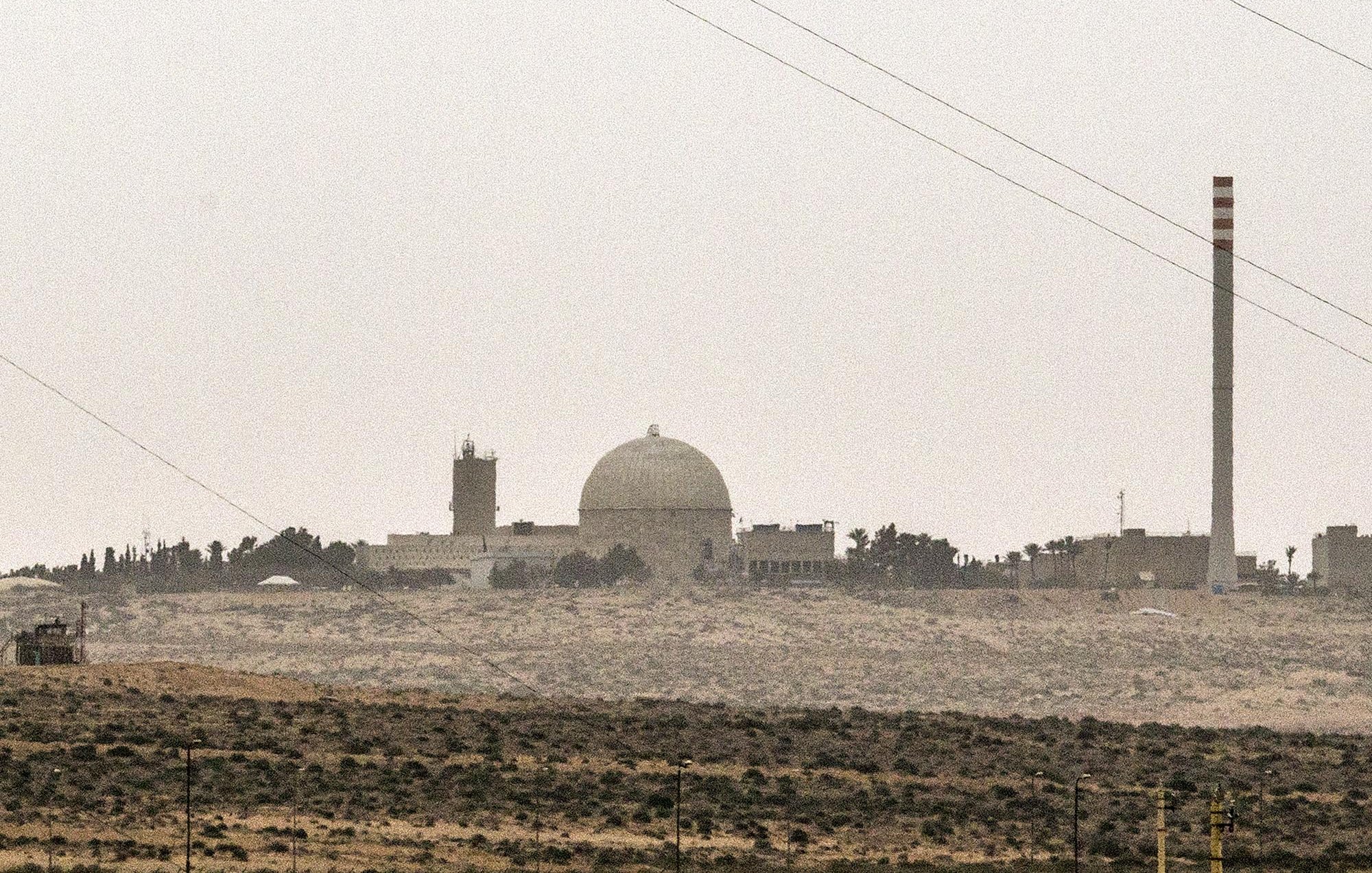 تصویر نمایی از یک تاسیسات صنعتی یا علمی را نشان می‌دهد که دارای یک گنبد بزرگ و چند ساختمان دیگر است. در سمت راست تصویر، یک دودکش بلند به چشم می‌خورد که ممکن است مربوط به فعالیت‌های صنعتی باشد. فضای اطراف تصویر سرسبز نیست و بیشتر به بیابان یا زمین‌های خشک مشابهت دارد. آسمان نیز ابری و کدر به نظر می‌رسد. این تصویر ممکن است به یک مرکز تحقیقاتی یا نیروگاه اشاره داشته باشد.
