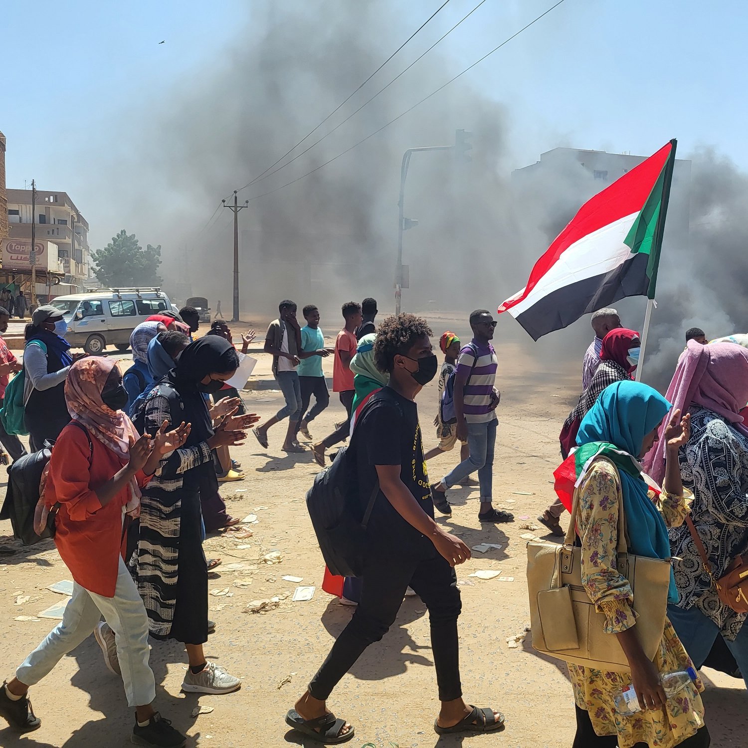 Un gruppo di persone in marcia, con bandiere, in un ambiente di protesta fumatore.