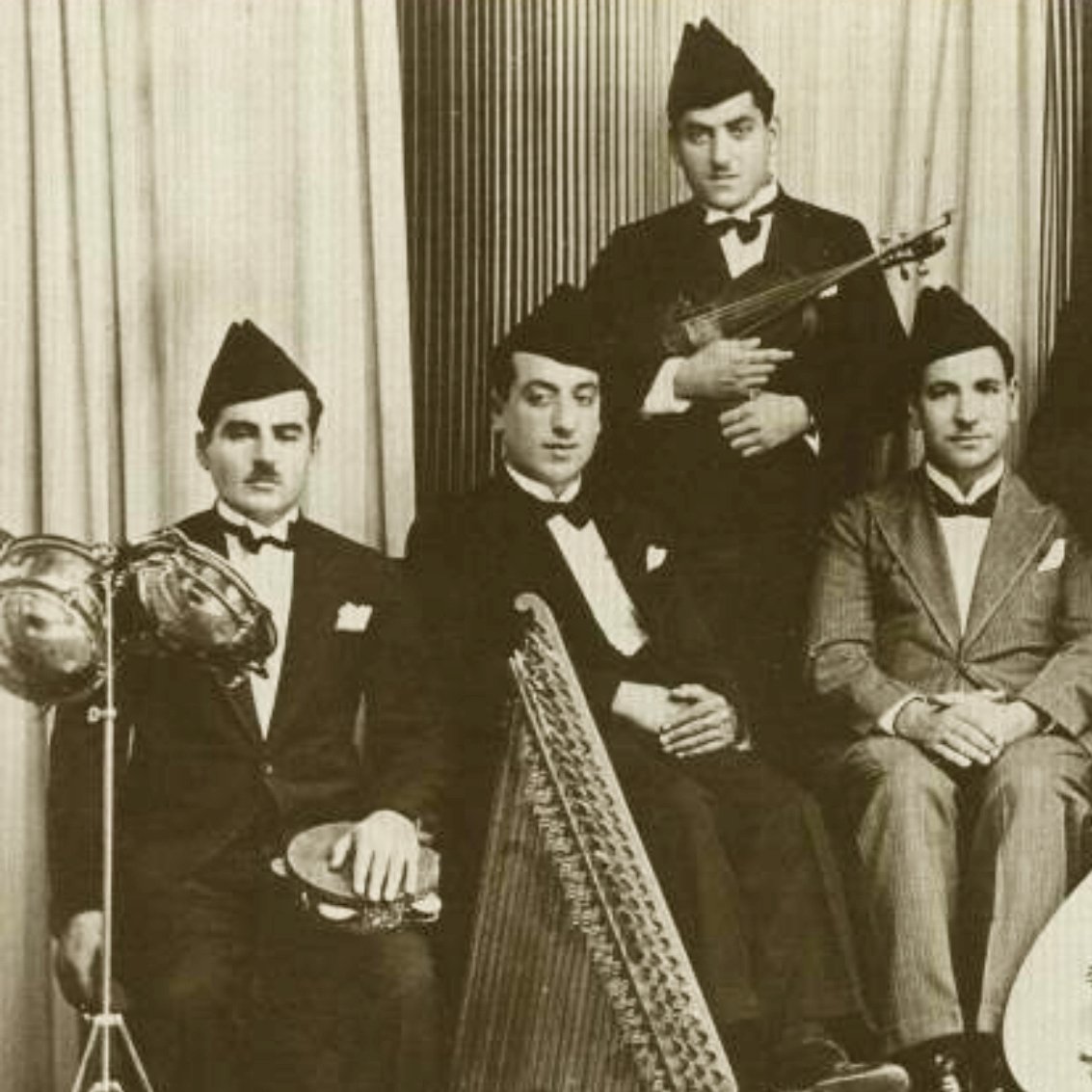 مجموعة من الموسيقيين يرتدون بدلات رسمية ويعزفون آلات موسيقية متنوعة.