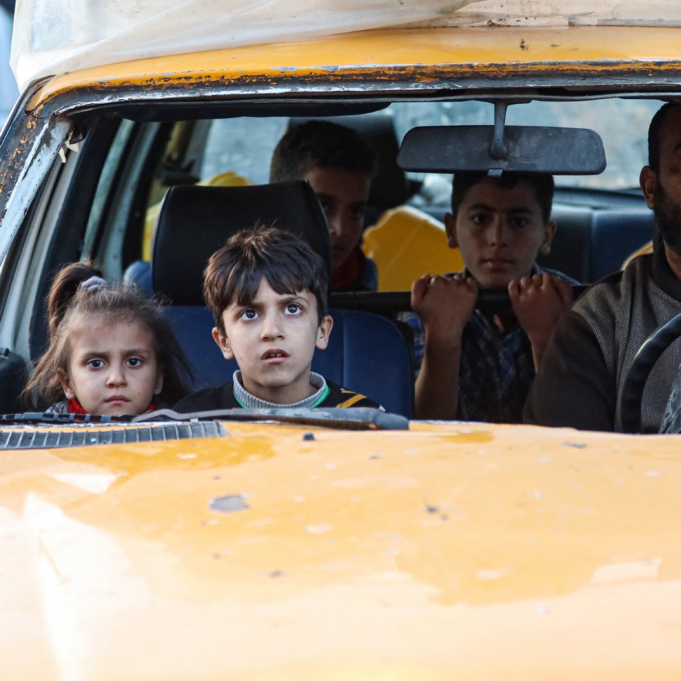 درون یک تاکسی زرد، مردی در حال رانندگی است و چهار کودک با نگاه‌های حیرت‌زده نشسته‌اند.