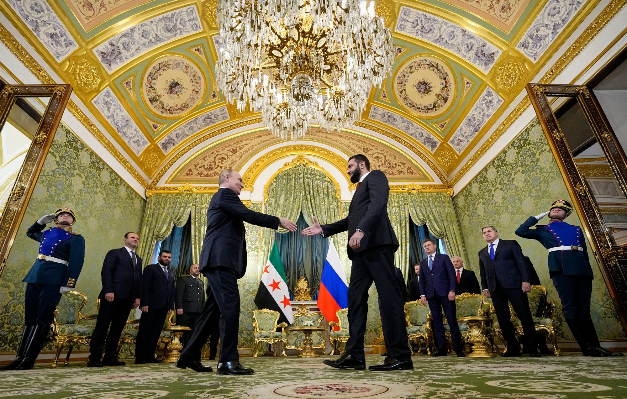 A formal meeting in an ornate room, with leaders shaking hands and military personnel in uniform.